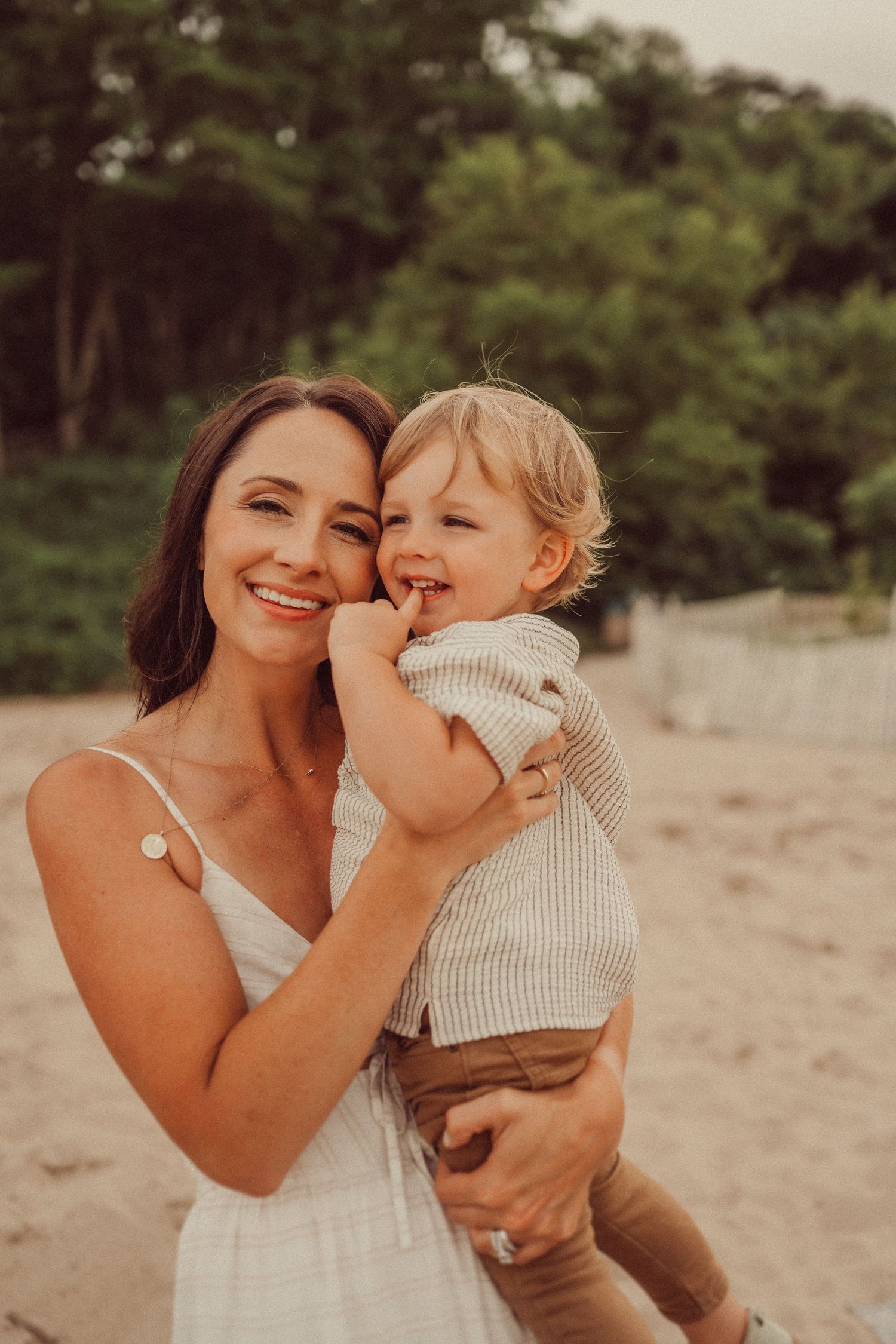Mother and toddler share laughter during golden hour beach portrait session.