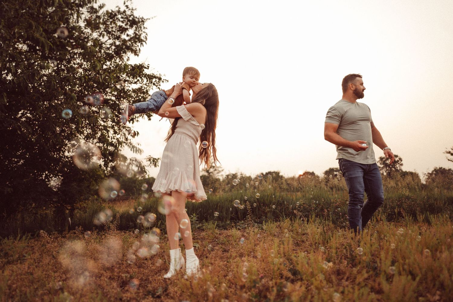 A joyful outdoor moment with white dress and boots in a rustic field at dusk.