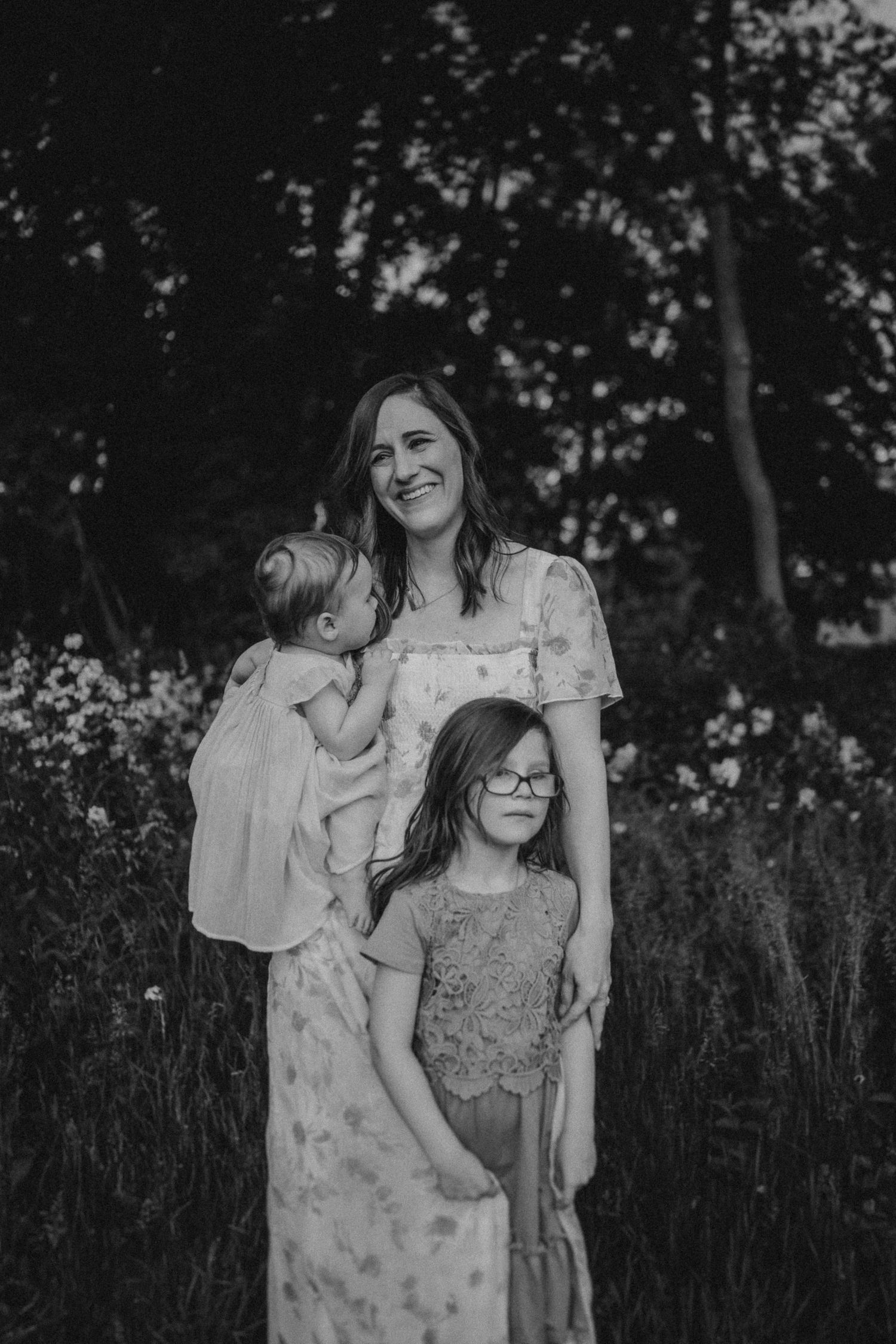 A black and white portrait of a family surrounded by wildflowers and trees.