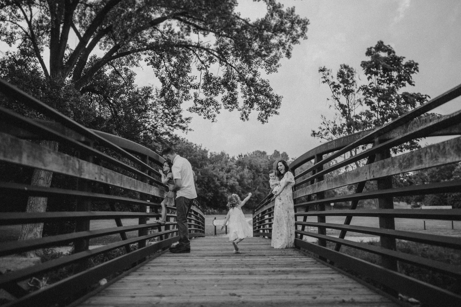 Black and white photo of a tender moment on a wooden bridge in nature.