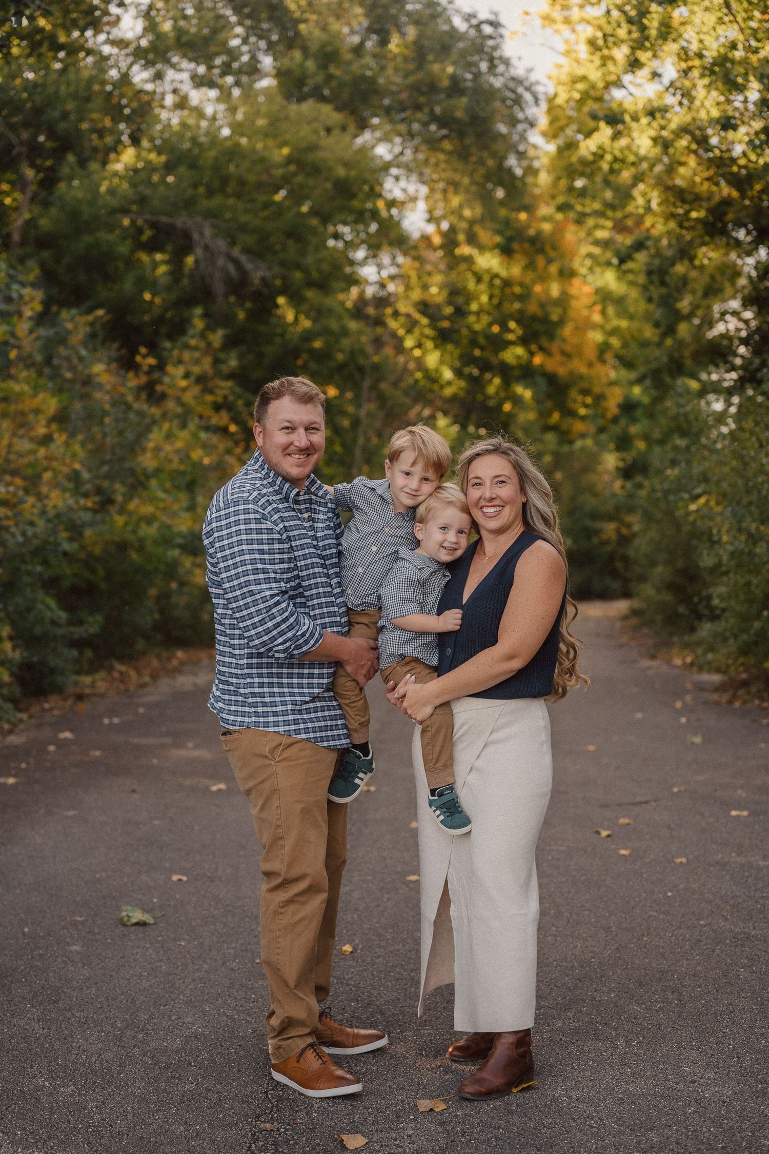 A family shares joyful moments together on a tree-lined path during golden hour.