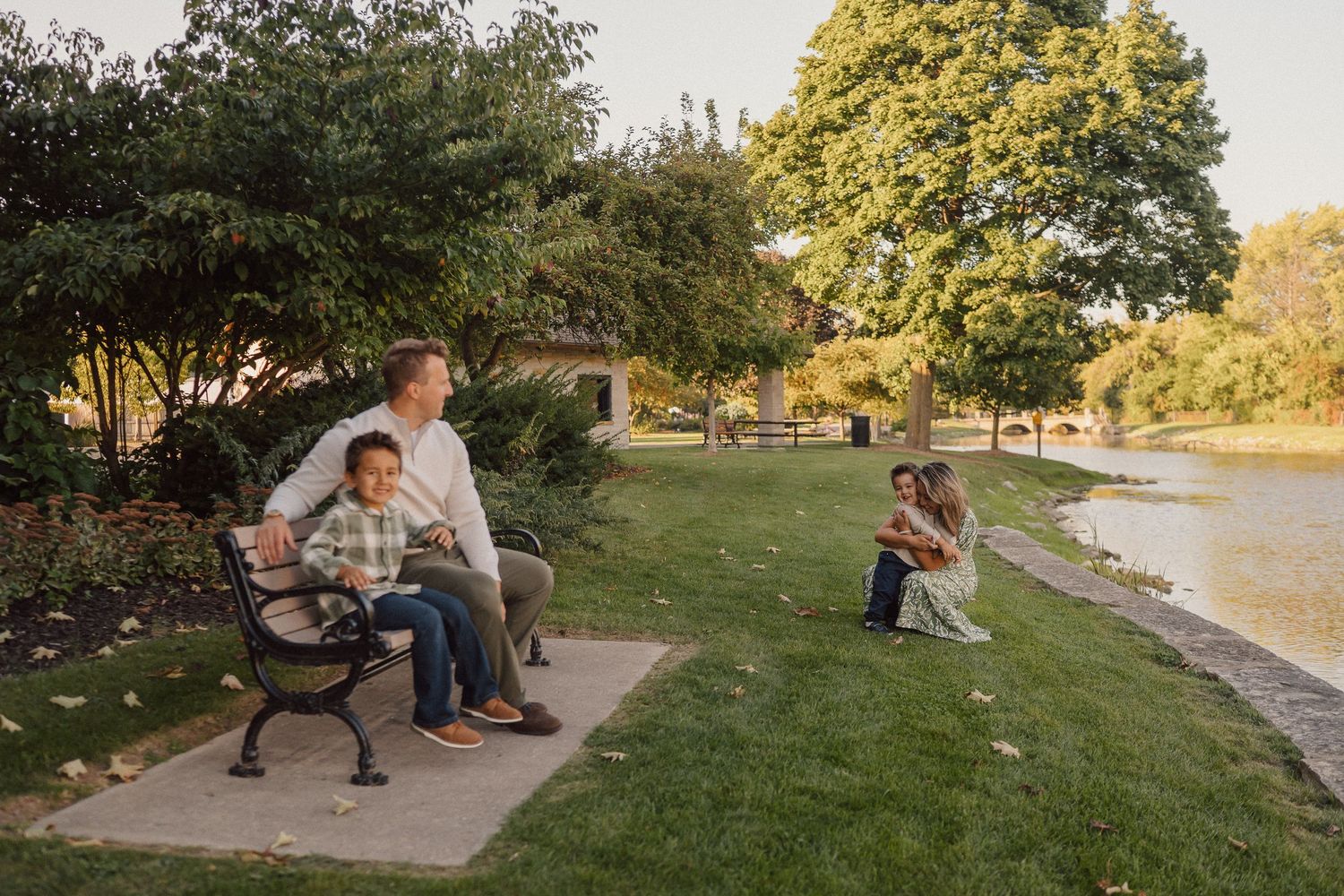 A series of candid outdoor family photos taken at sunset in a grassy park setting with trees in the background.
