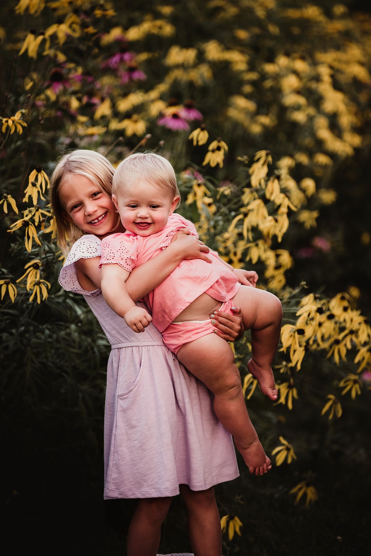 Joyful children hugging and laughing together among yellow and purple flowers.