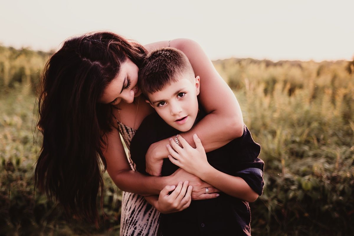 Mother and child share tender moment while embracing in an outdoor setting.