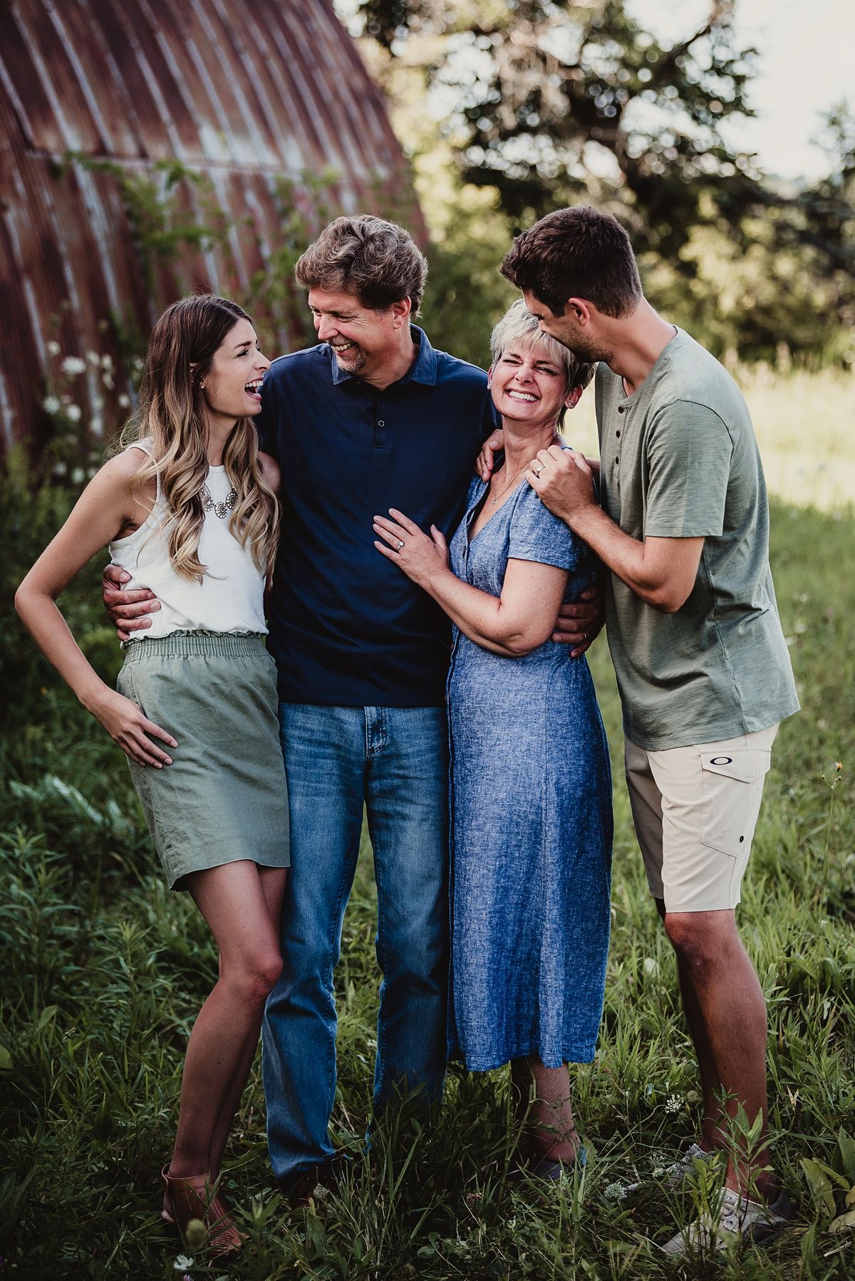 Candid family photo with laughter against a rustic barn backdrop.