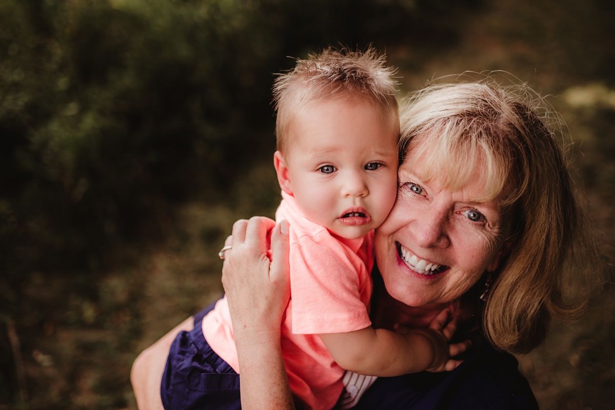A joyful outdoor portrait featuring a warm embrace against a natural wooded backdrop.