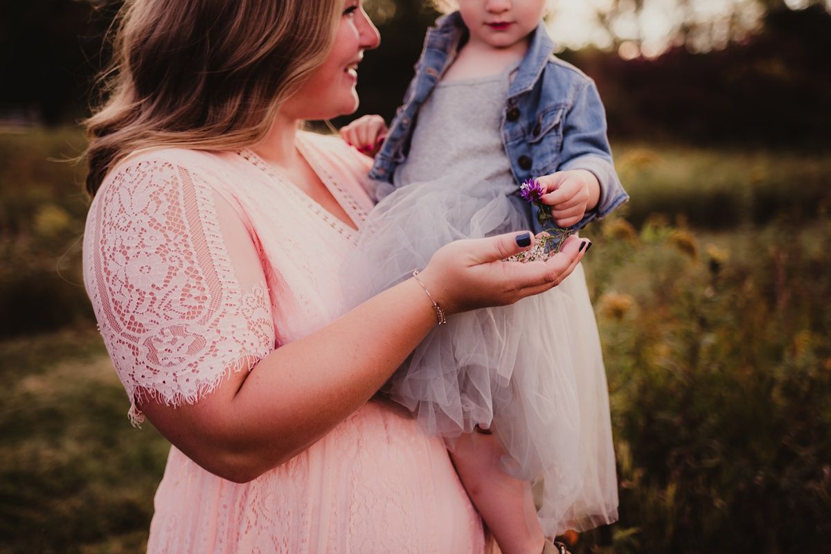 Close-up shot of parent and child in matching pink and tulle outfits during outdoor photoshoot.