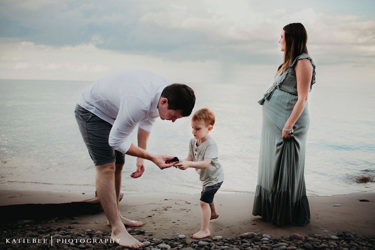 Family enjoys a playful moment together on a beach during sunset.