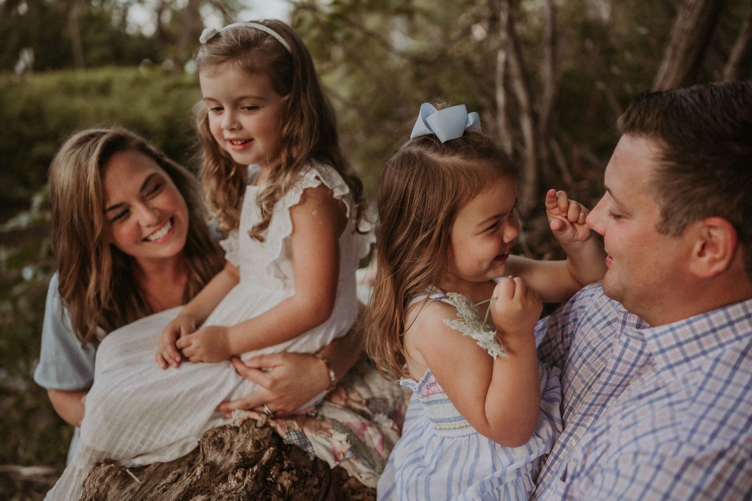 Intimate family photo showing genuine laughter and connection while sitting together outdoors.