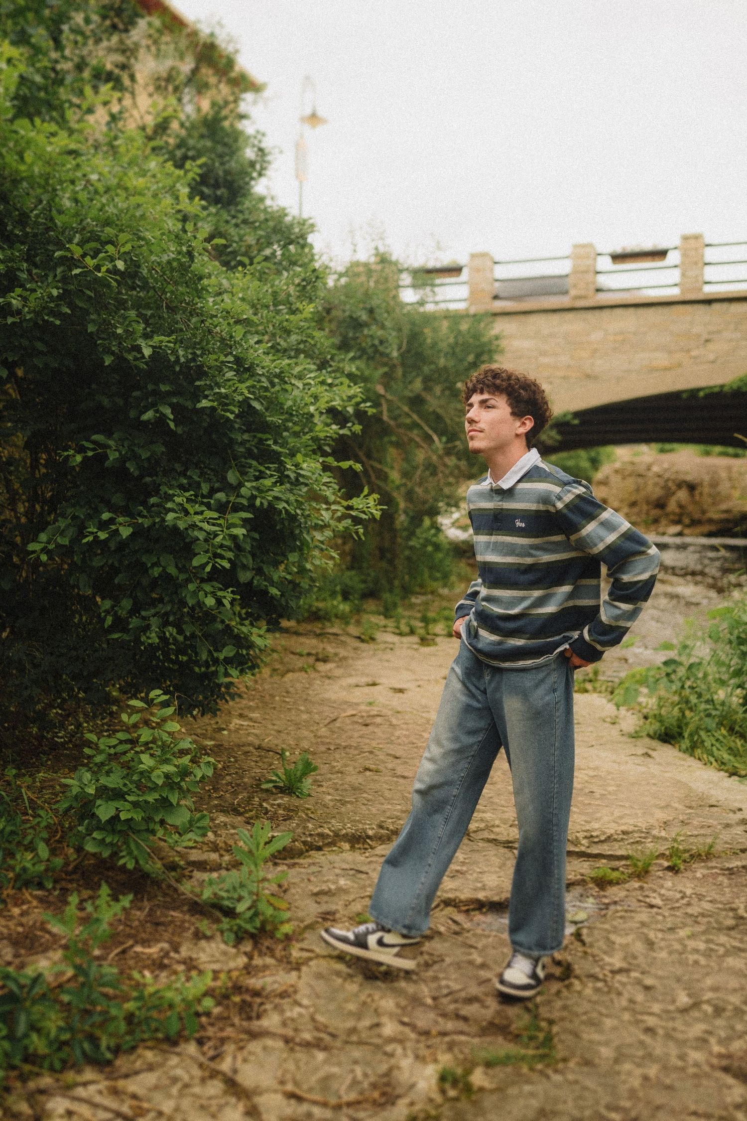 A casual scene by a bridge with stone path and lush greenery in natural lighting.