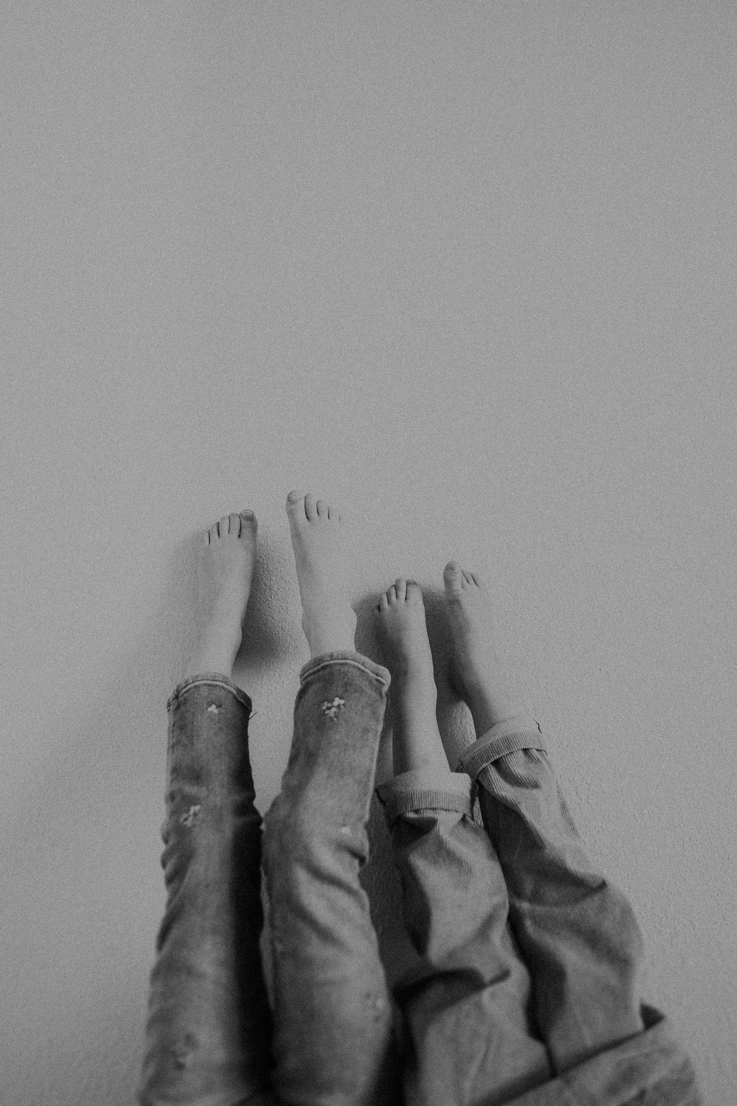 Black and white photo of bare feet raised in the air against a light background.