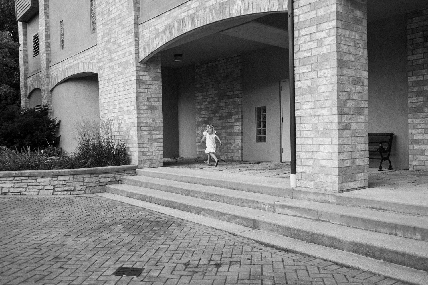 Black and white architectural photograph showing a series of brick archways and columns in a covered walkway.