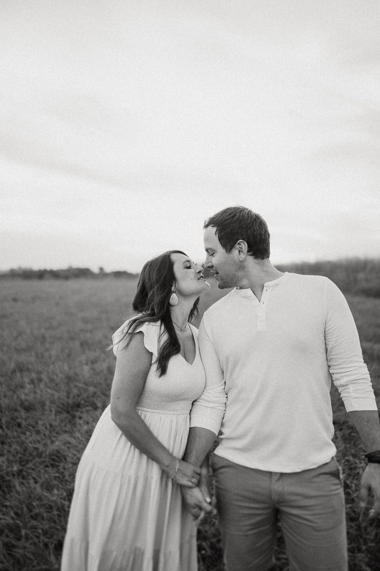 Black and white intimate portrait of couple sharing a moment in a field.