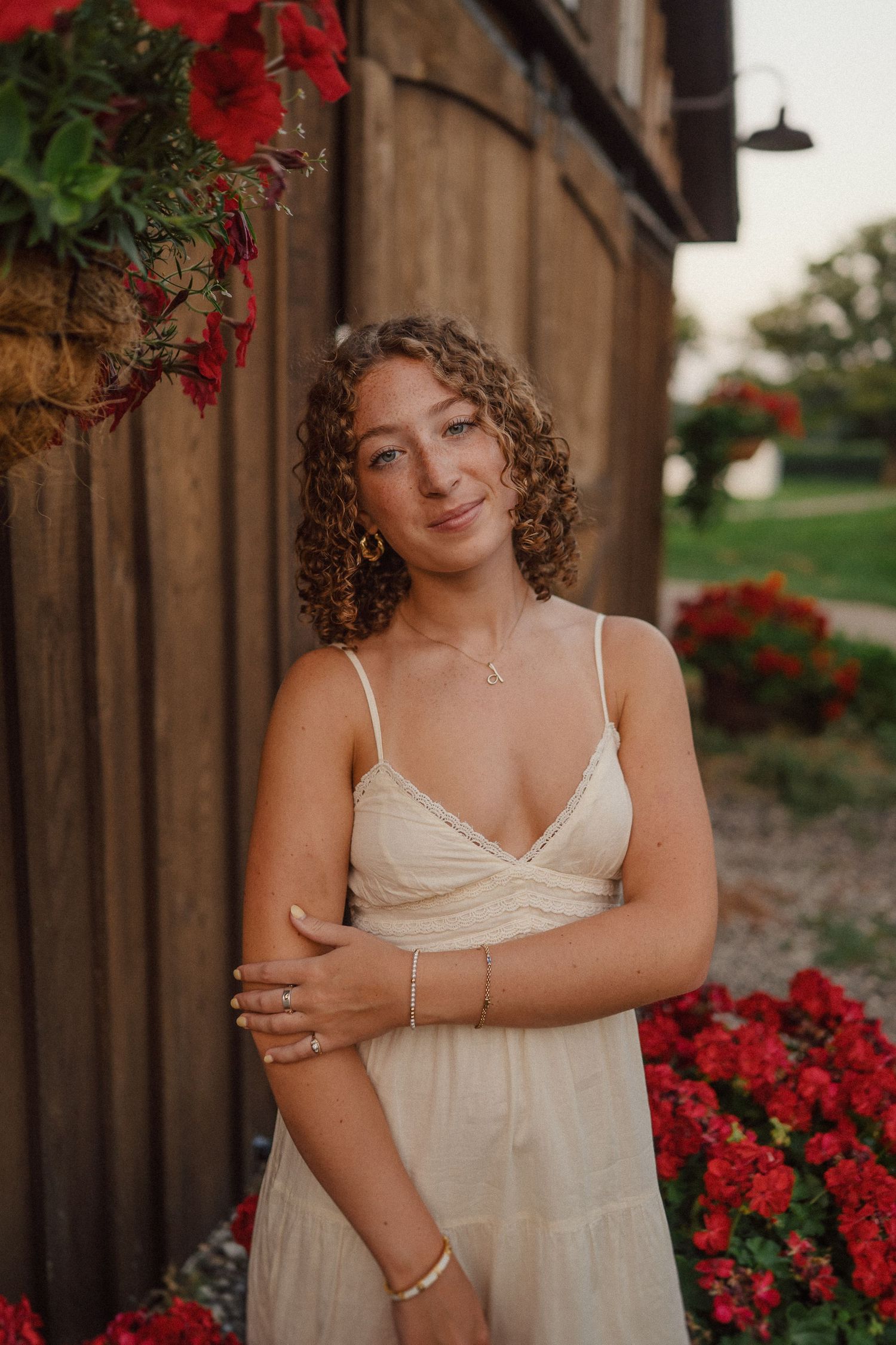 Portrait against rustic wooden wall with blooming red flowers and natural summer evening lighting.