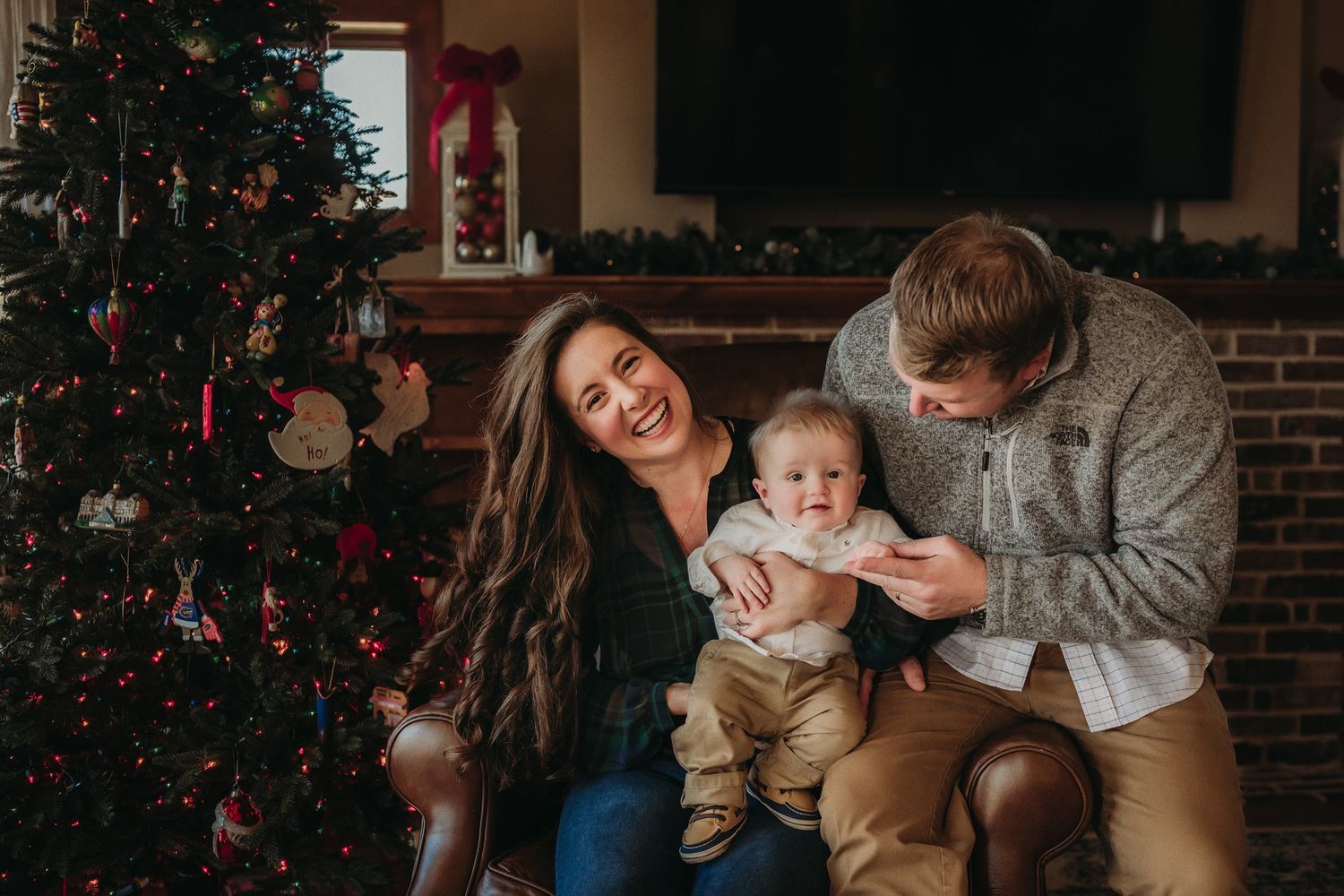 Family shares intimate moment together by decorated Christmas tree in living room.