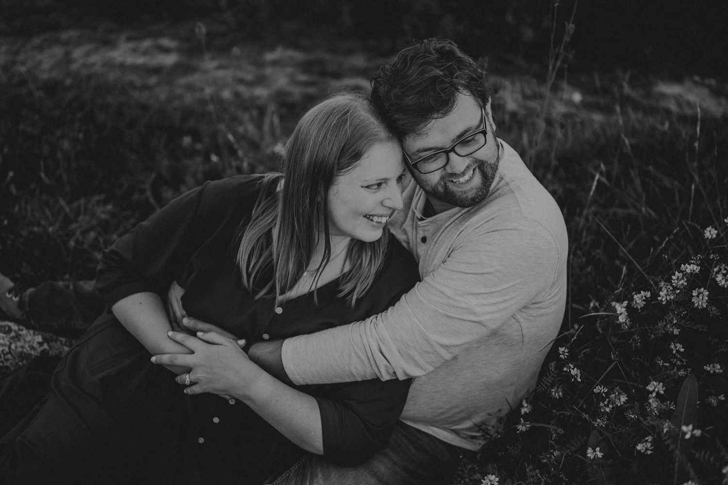 An intimate black and white portrait of a couple embracing outdoors.