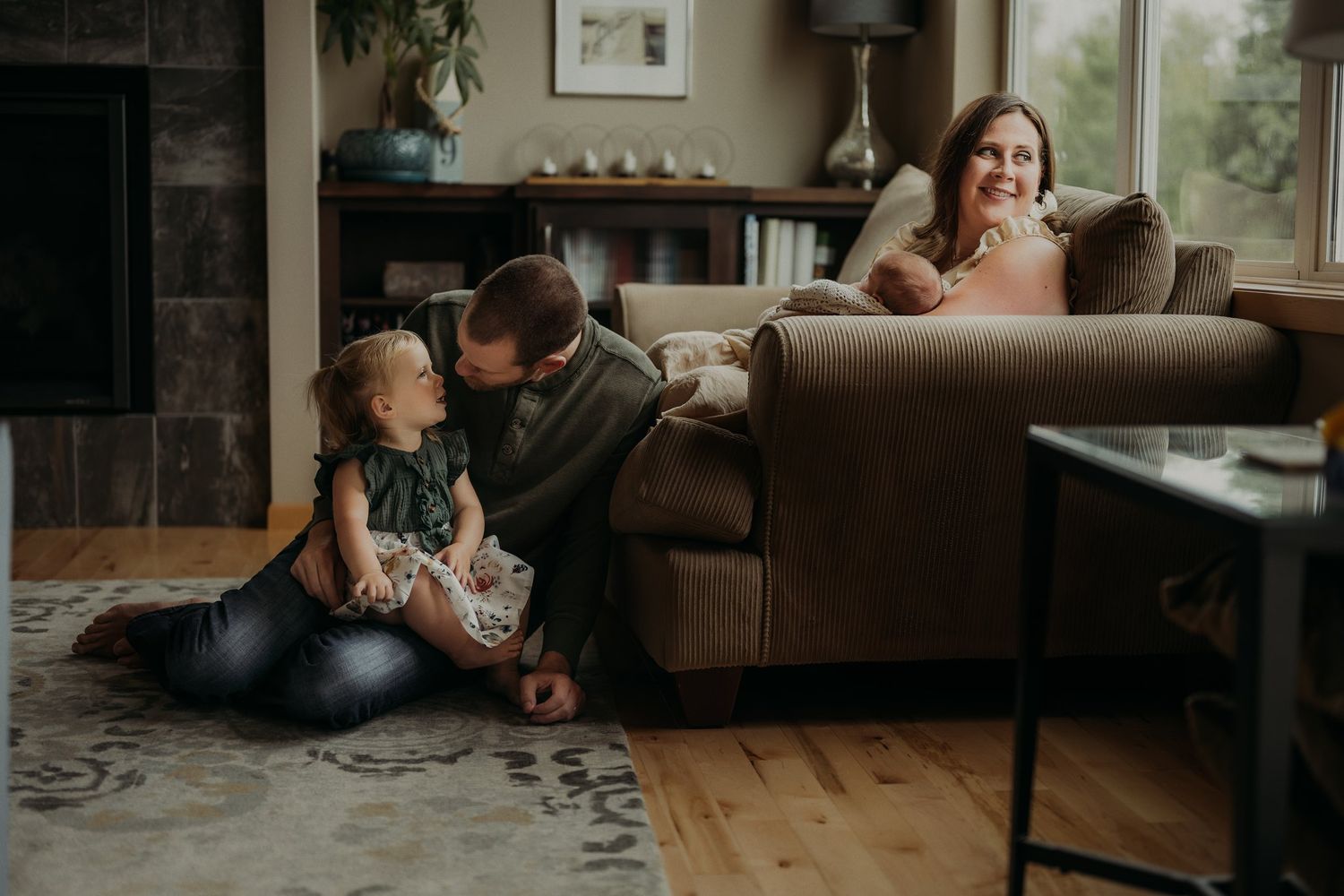 An intimate family moment shared in a living room with hardwood floors and comfortable furniture.