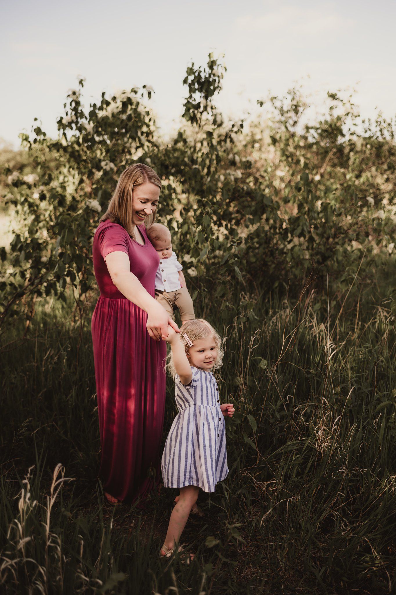 A gentle moment captured in nature with a burgundy-dressed figure dancing with a child in stripes.