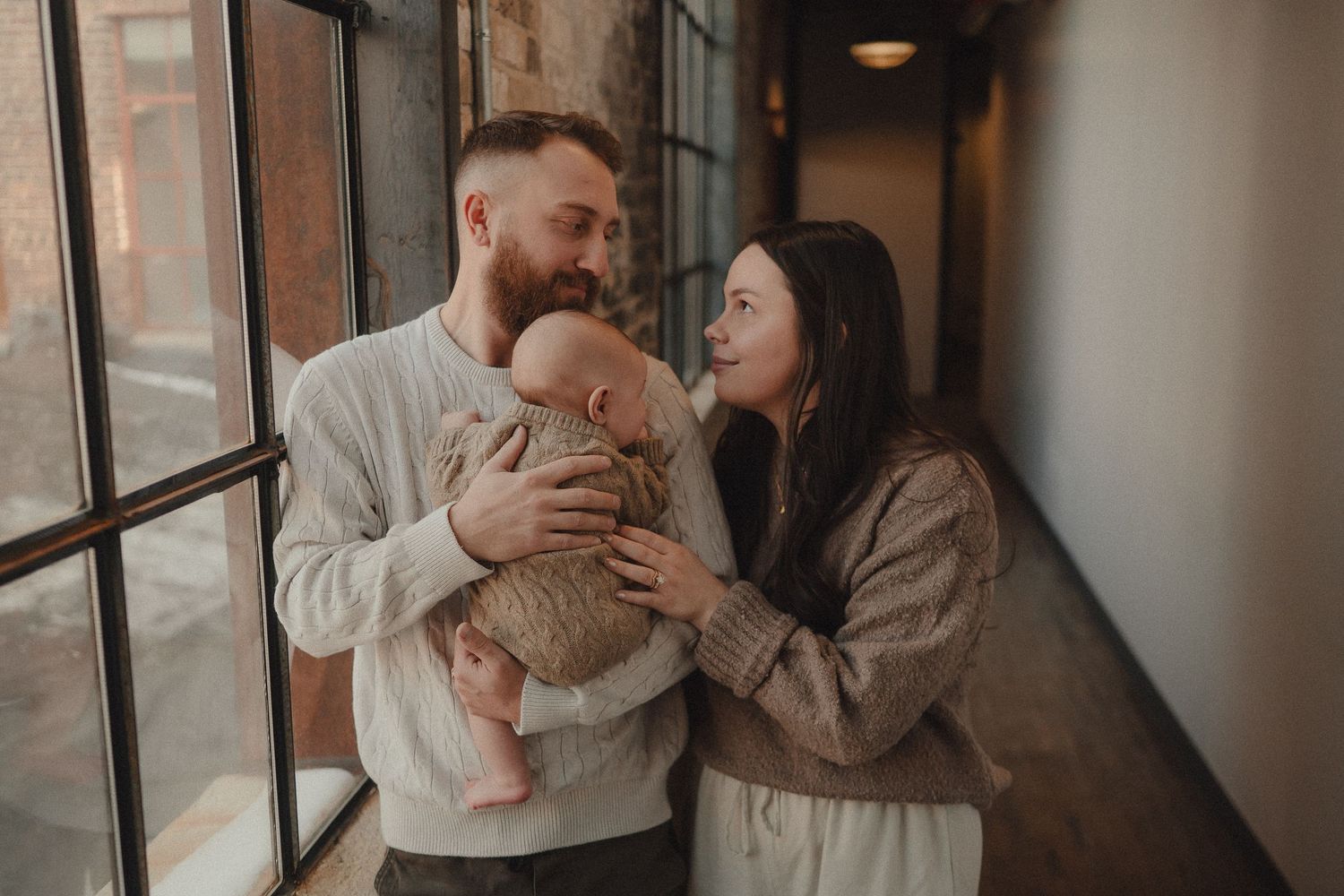 Couple sharing tender moments in a rustic hallway with brick walls.