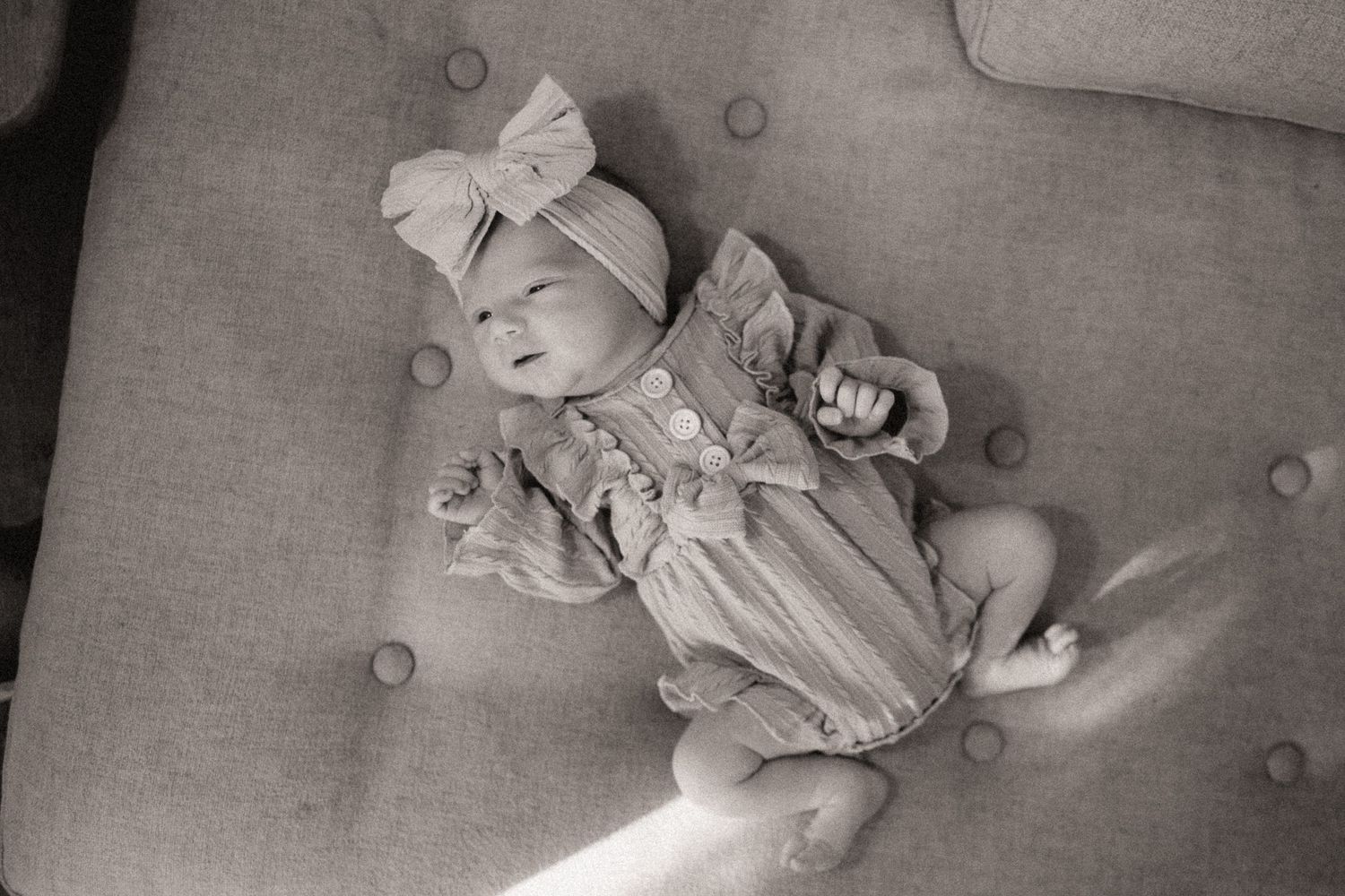 A peaceful scene of a baby resting on gray upholstery in soft, muted tones.