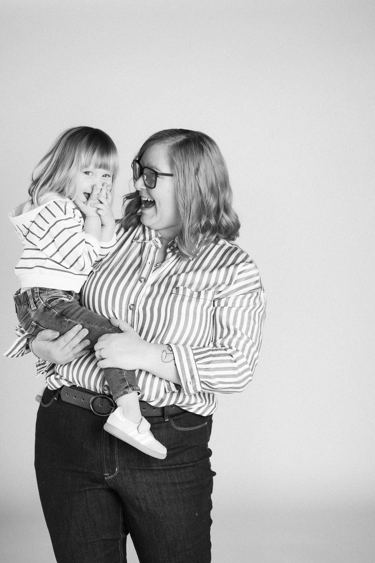 Two people in matching striped shirts and dark pants embrace in a series of black and white photographs.
