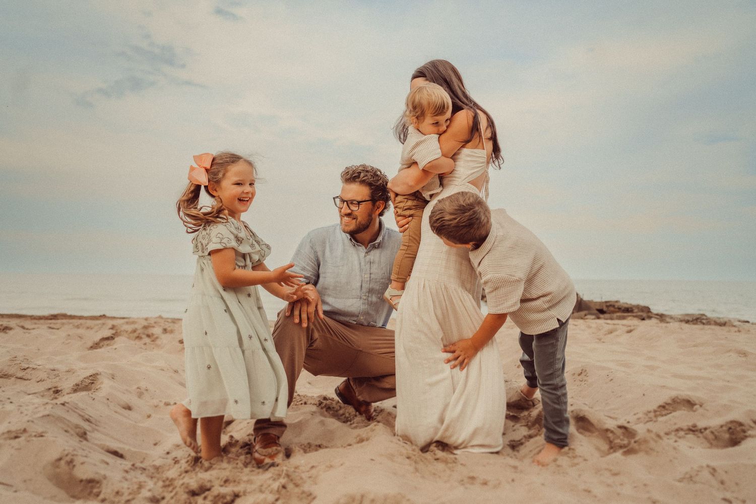 Family gathers together on sandy beach during sunset.