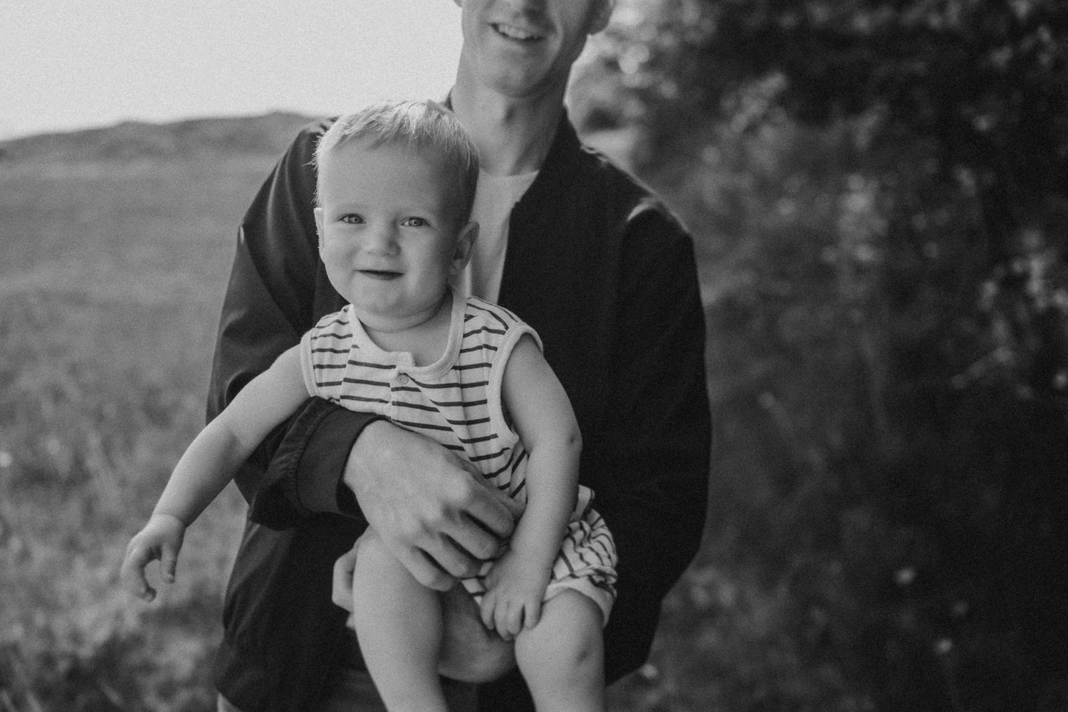 A black and white portrait showing a parent holding a small child in striped clothing.