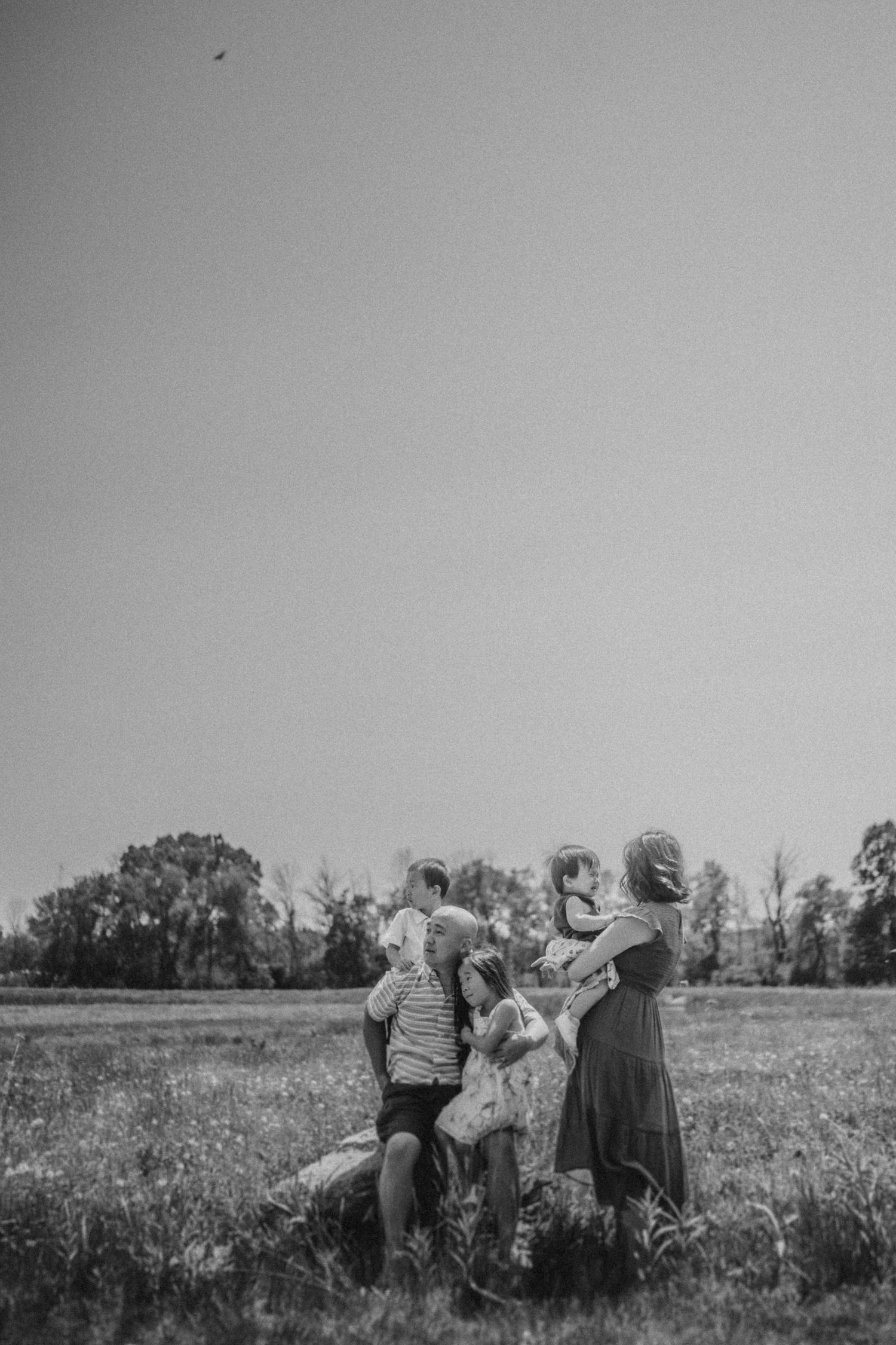 A candid black and white photo of a family playing in a grassy field.