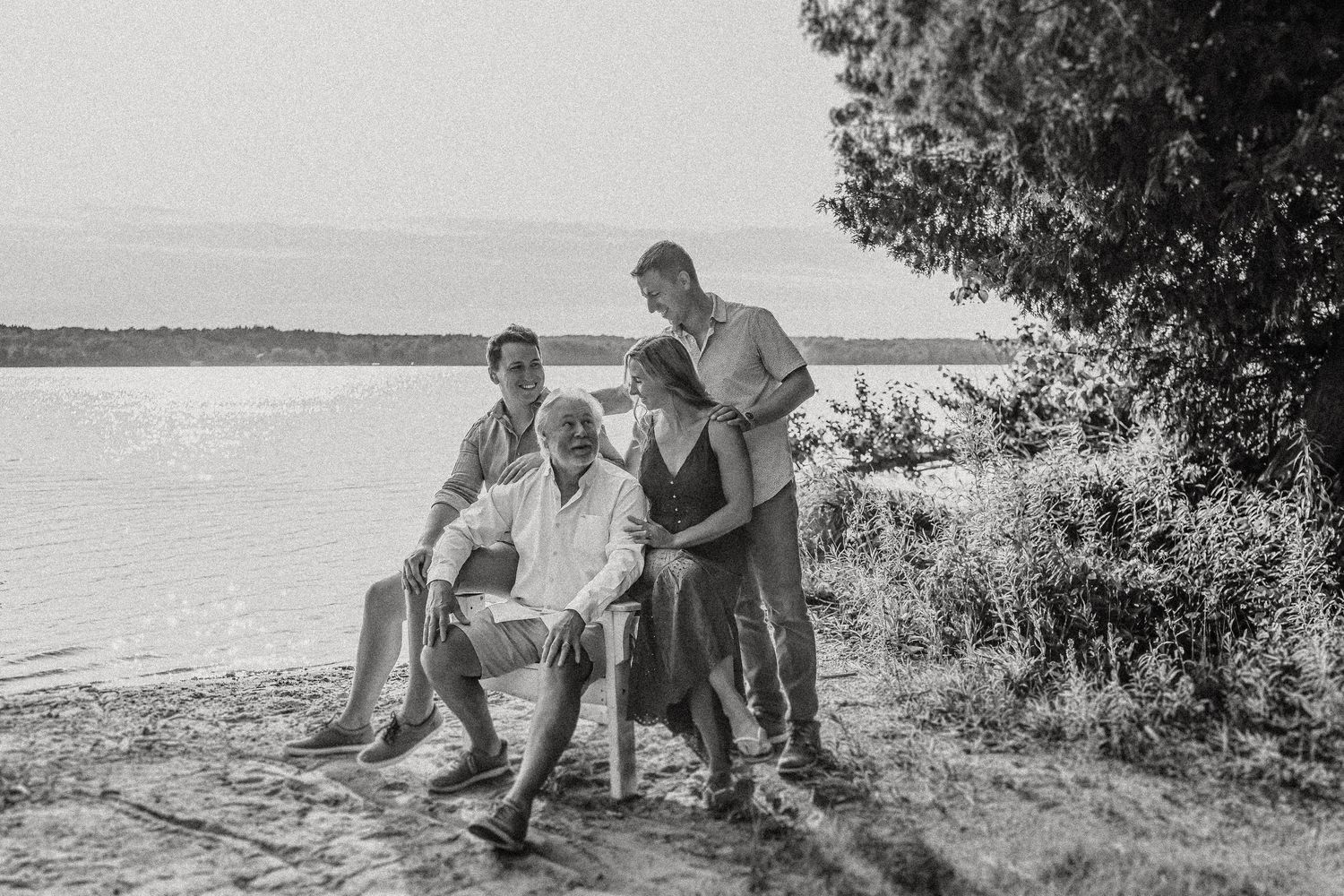 Black and white lakeside family photo with natural beach scenery.