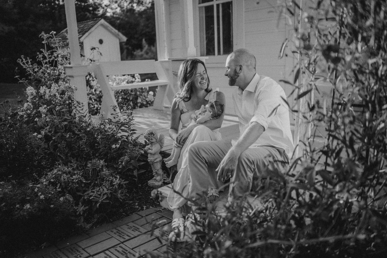 Black and white photo of a couple sharing an intimate moment on a rustic porch.