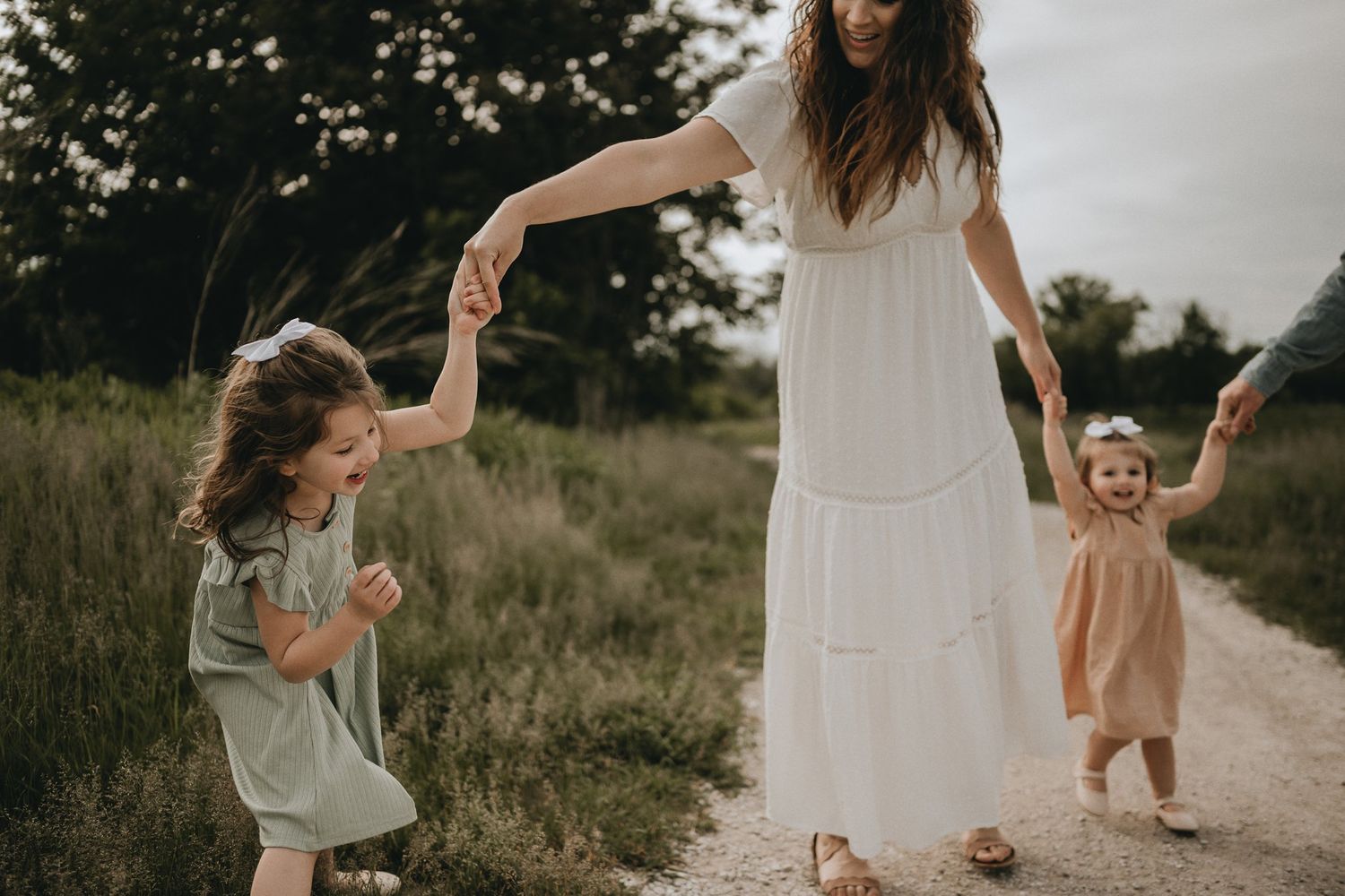 Dancing and twirling on a dirt path while wearing flowing dresses in warm evening light.