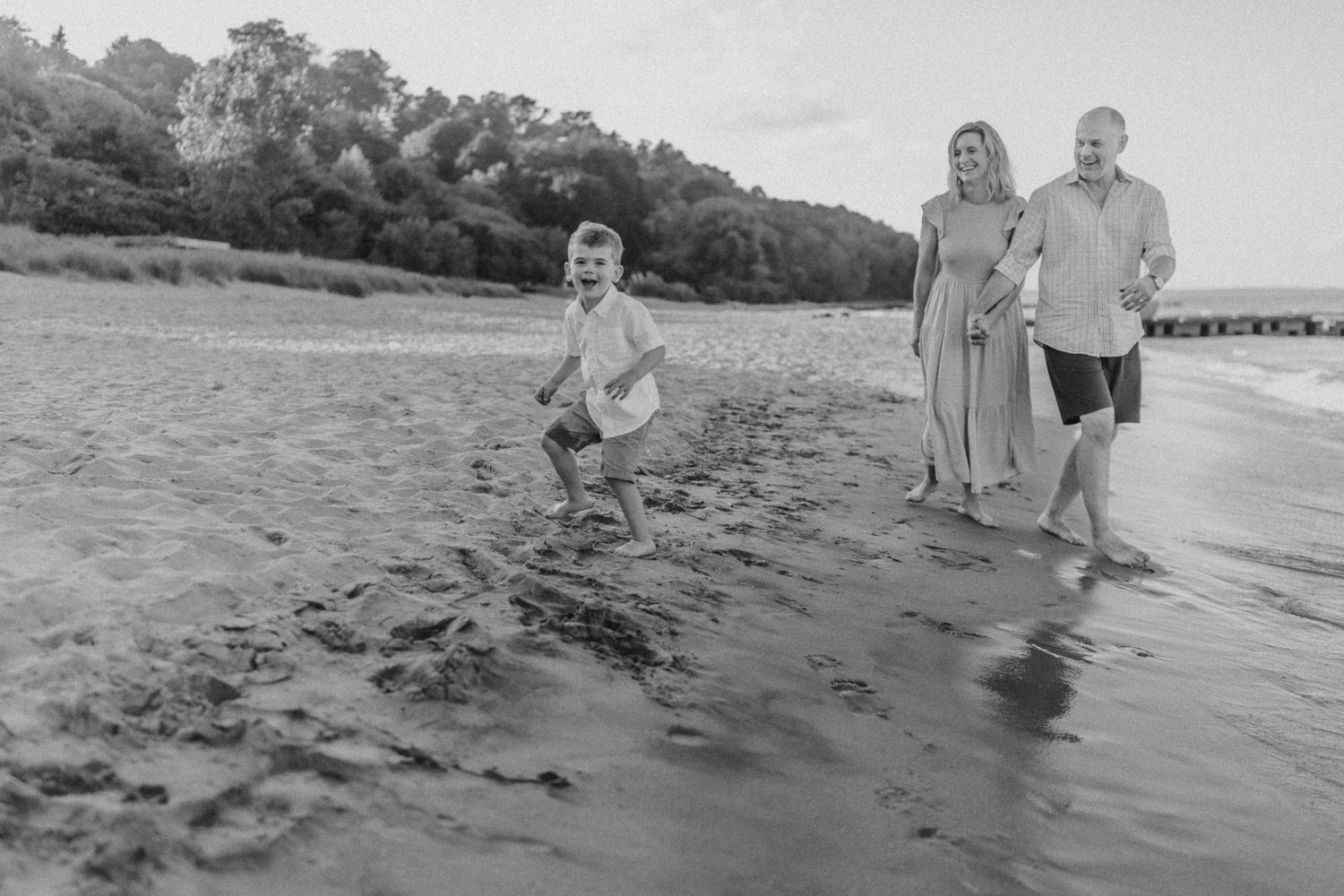 Black and white photo of a playful scene on a sandy beach with waves.