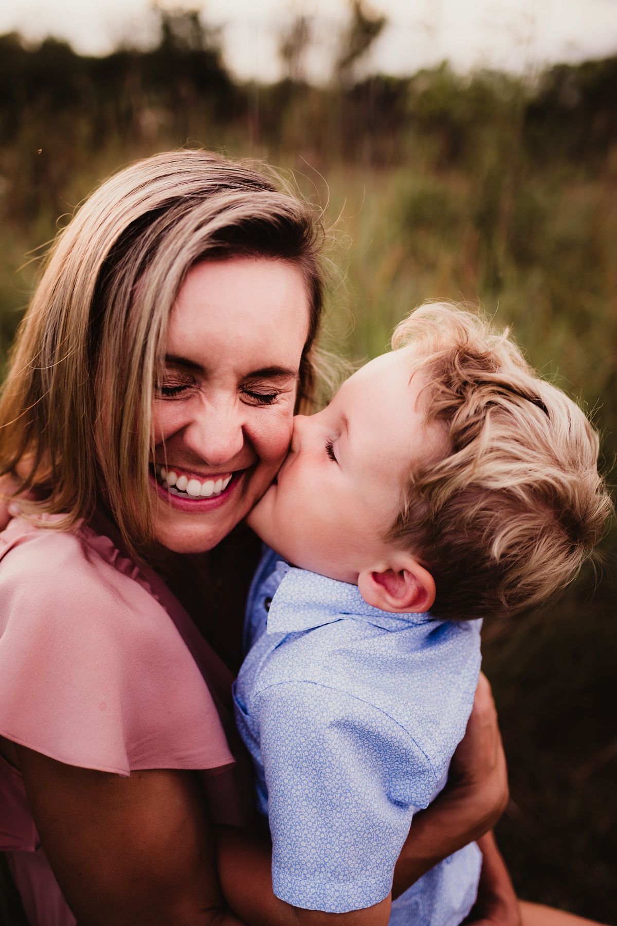Candid moment of affection captured during sunset family photoshoot in nature.