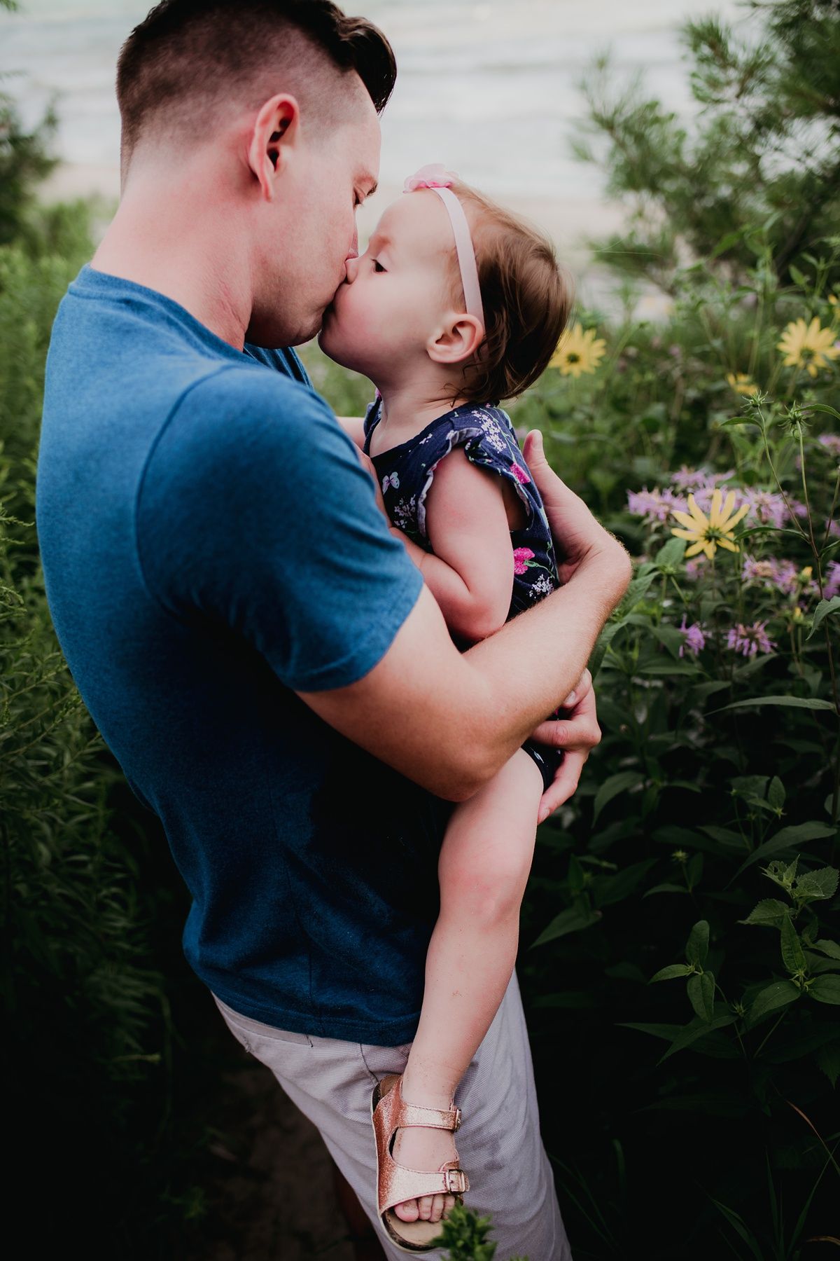 A touching moment between parent and child surrounded by blooming flowers in a garden.