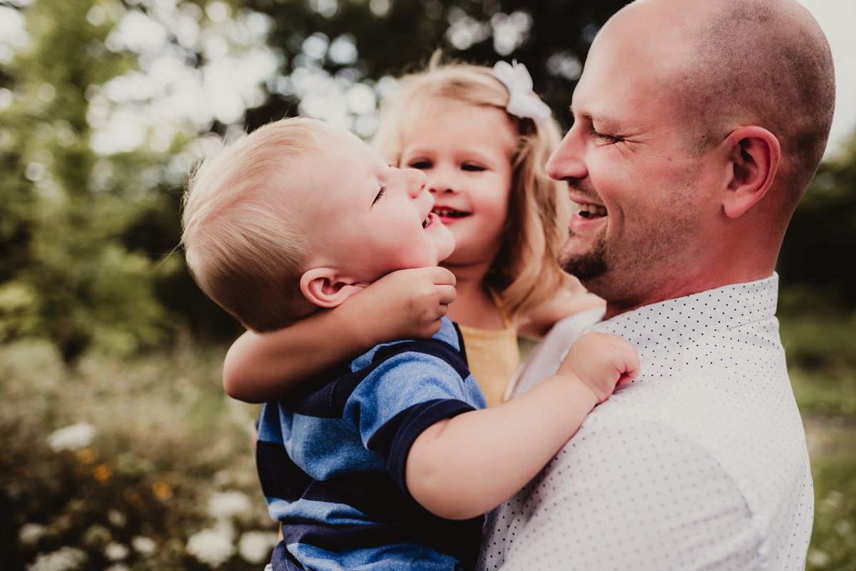 Joyful outdoor family moment captured against green foliage background.