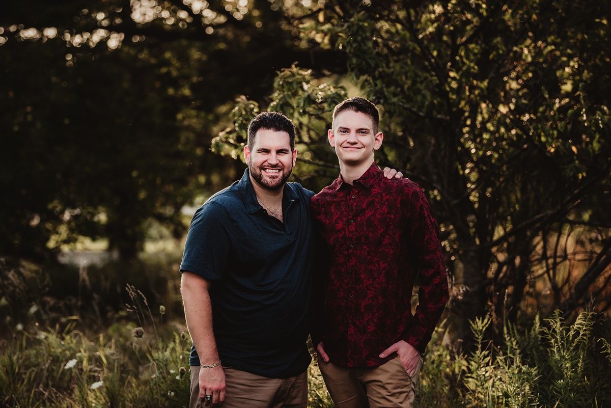 Two people standing together in a field during golden hour portrait session.