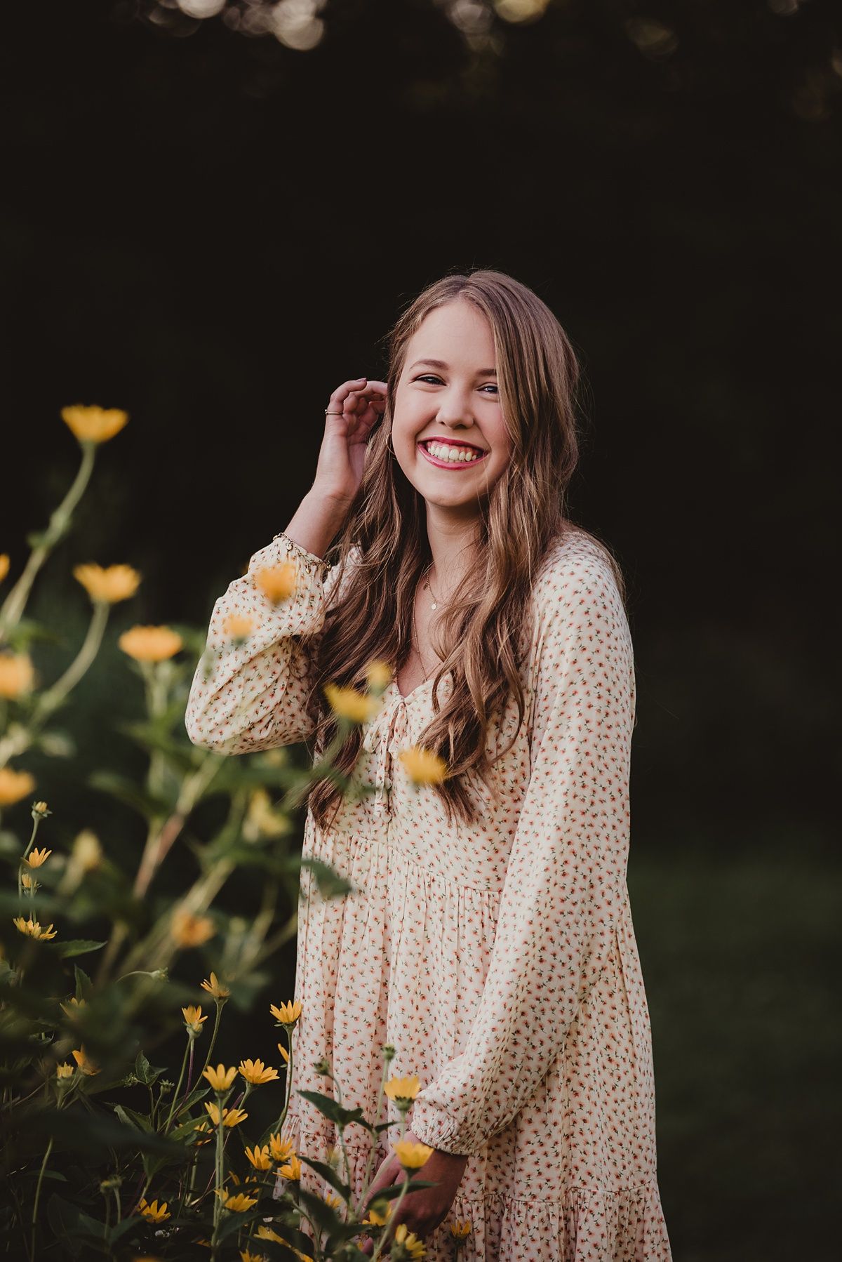 Summer garden portrait with yellow flowers and cream polka dot dress in natural setting.
