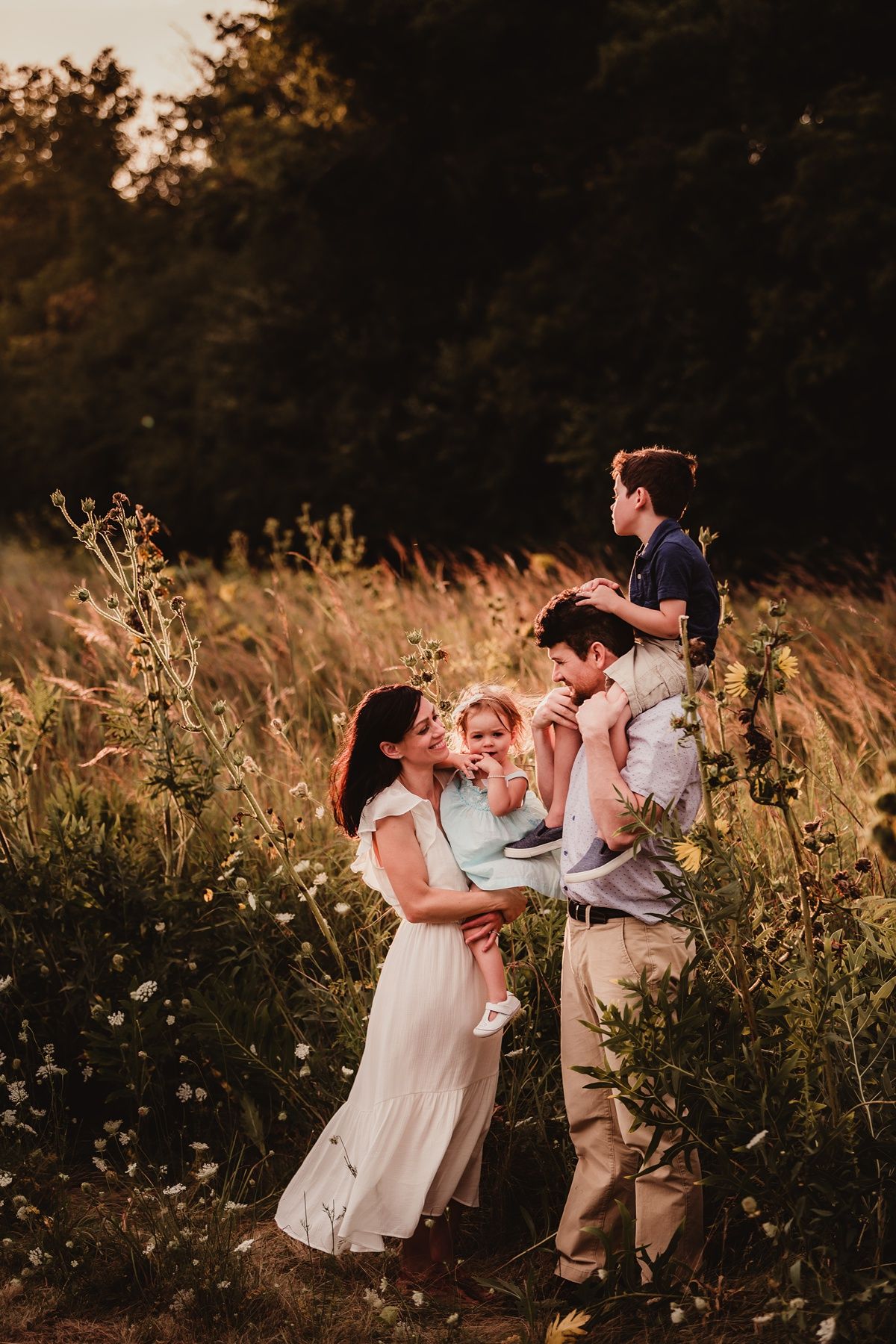 Family sharing joyful moment together in golden sunlit meadow at sunset.