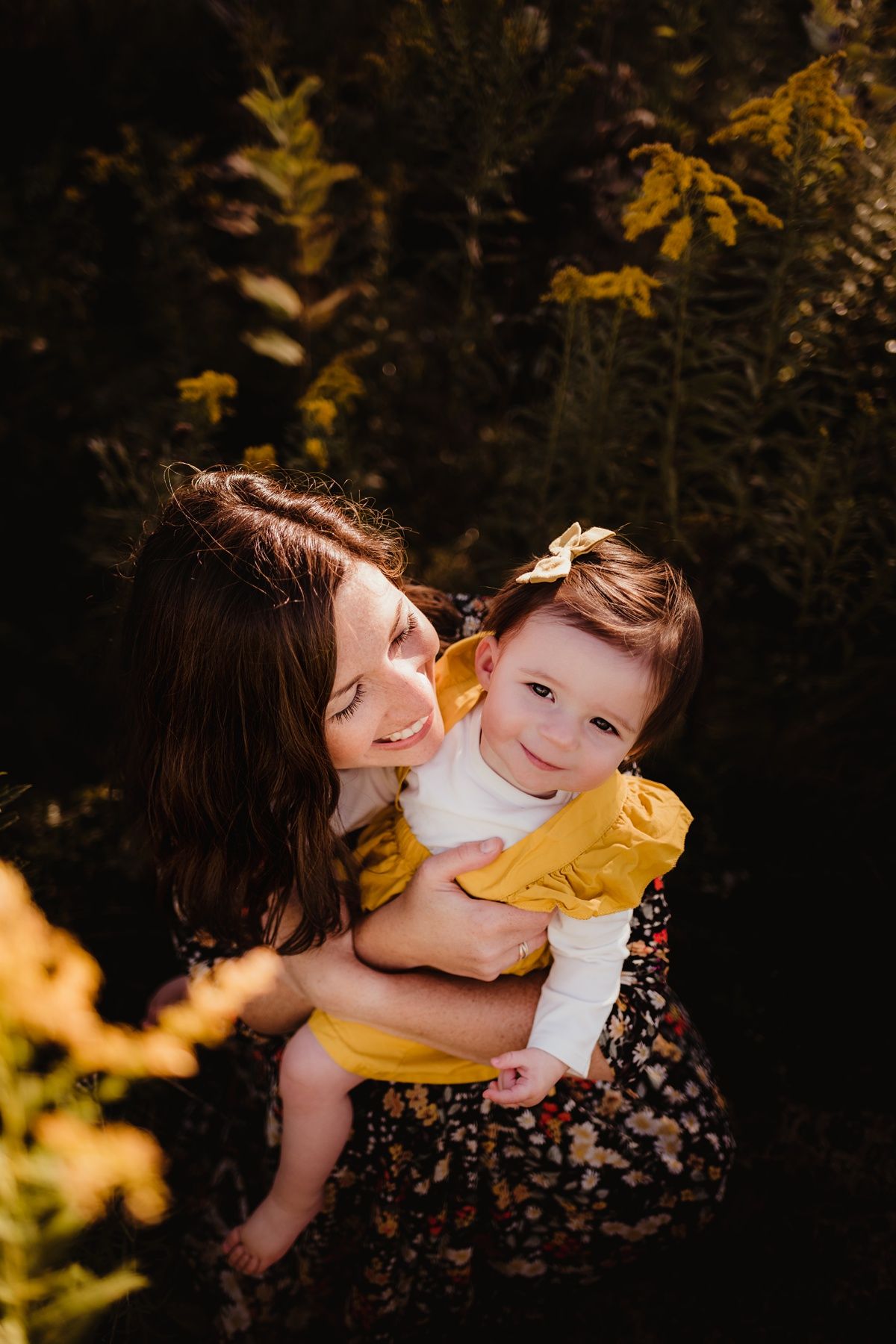 An intimate portrait of parent and child embracing among golden autumn foliage.