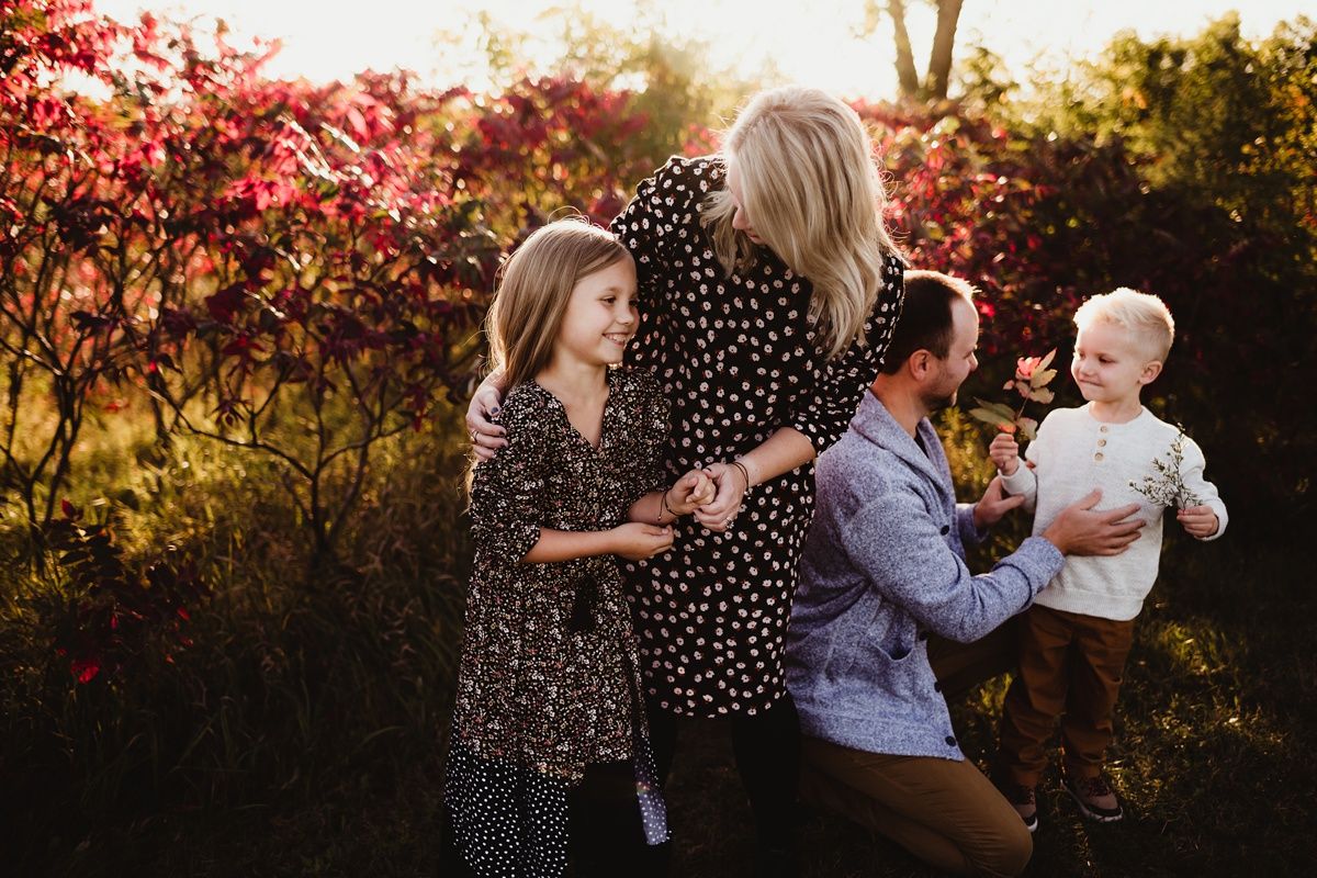 A playful family photo session among autumn foliage during golden hour.