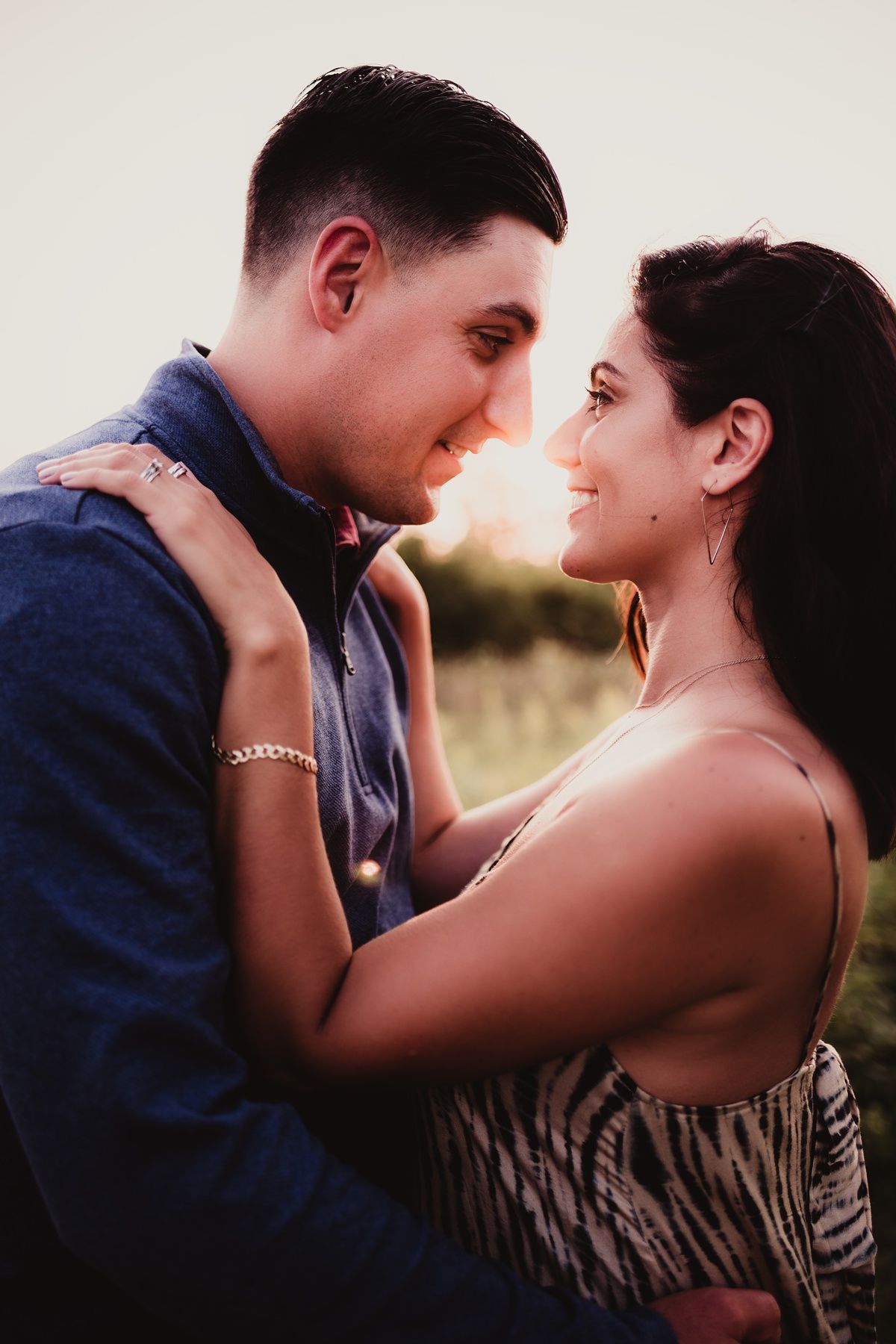 Loving couple embracing in casual attire during golden hour outdoor photo session.