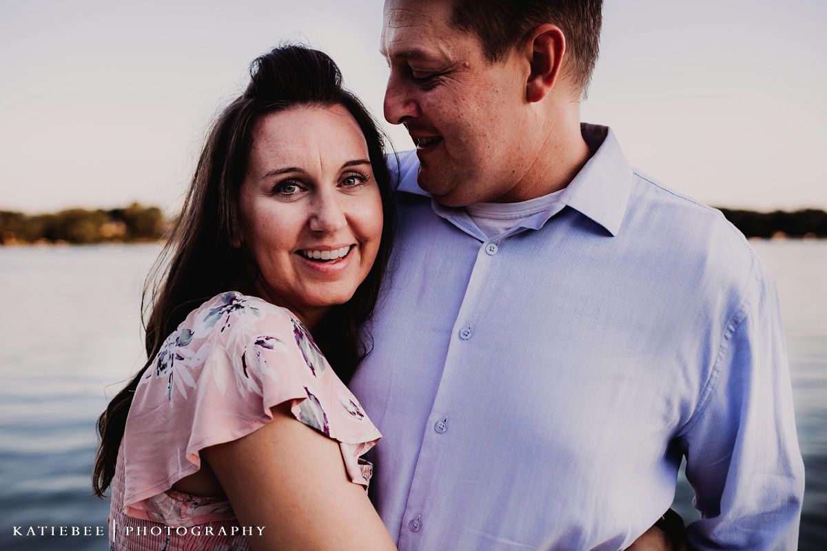 Romantic couple sharing intimate moment during lakeside sunset photoshoot.