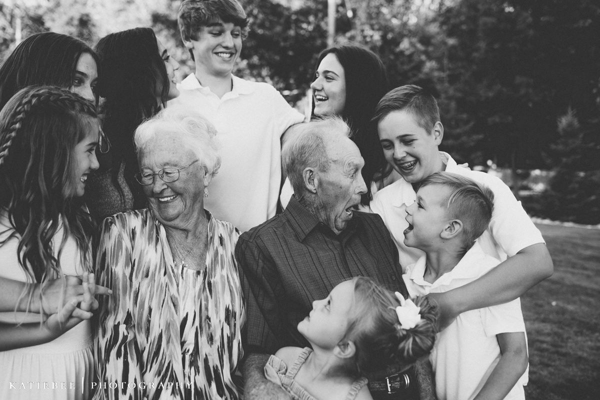 Black and white portrait of a multi-generational group sharing authentic laughter outdoors.