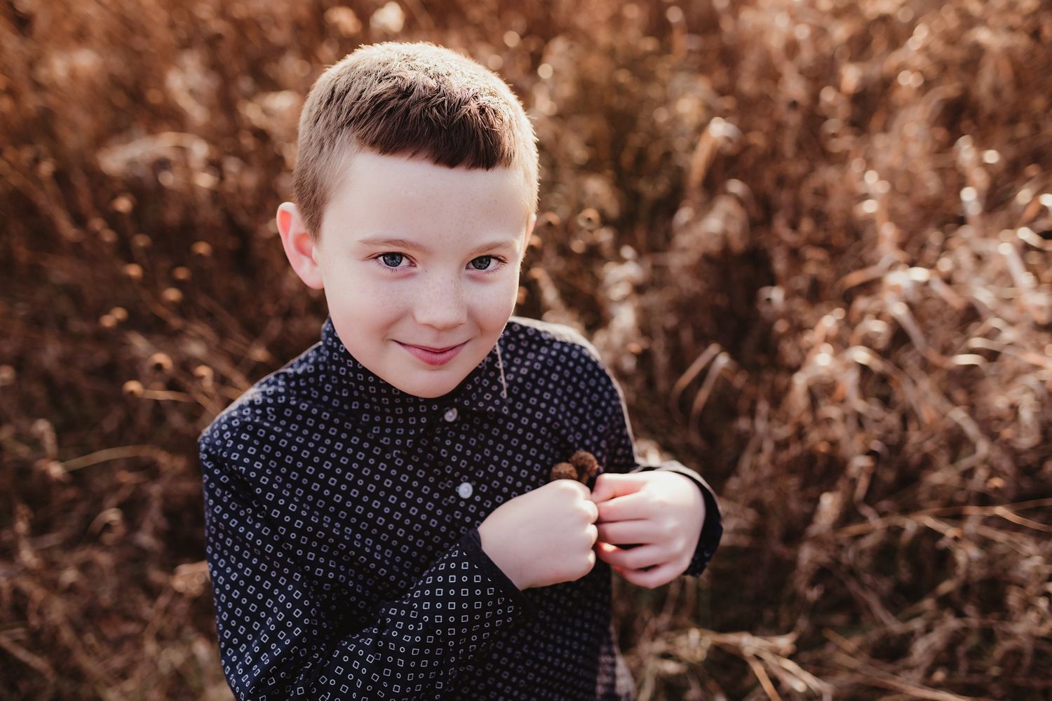 Close up portrait of young boy in polka dot shirt against autumn field.