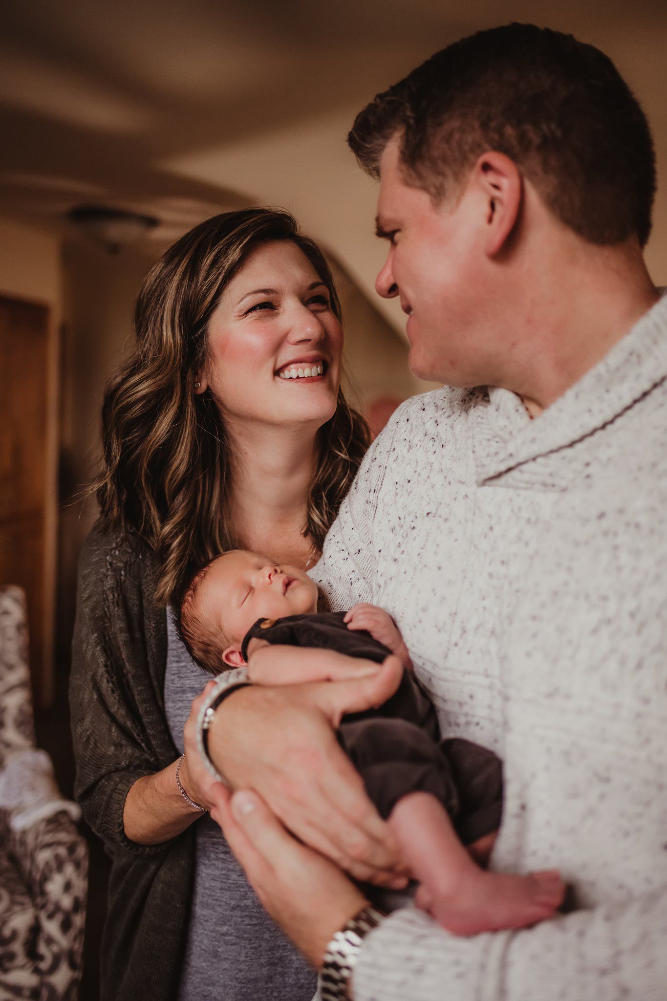 An intimate family moment captured indoors with a newborn baby and loving expressions.