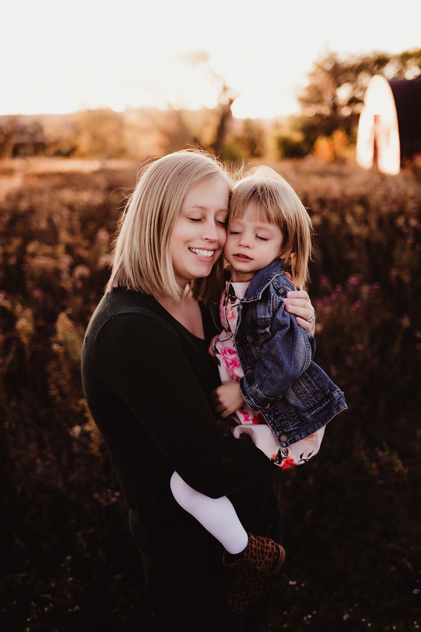 Warm sunset portrait of parent and child embracing outdoors in natural setting.