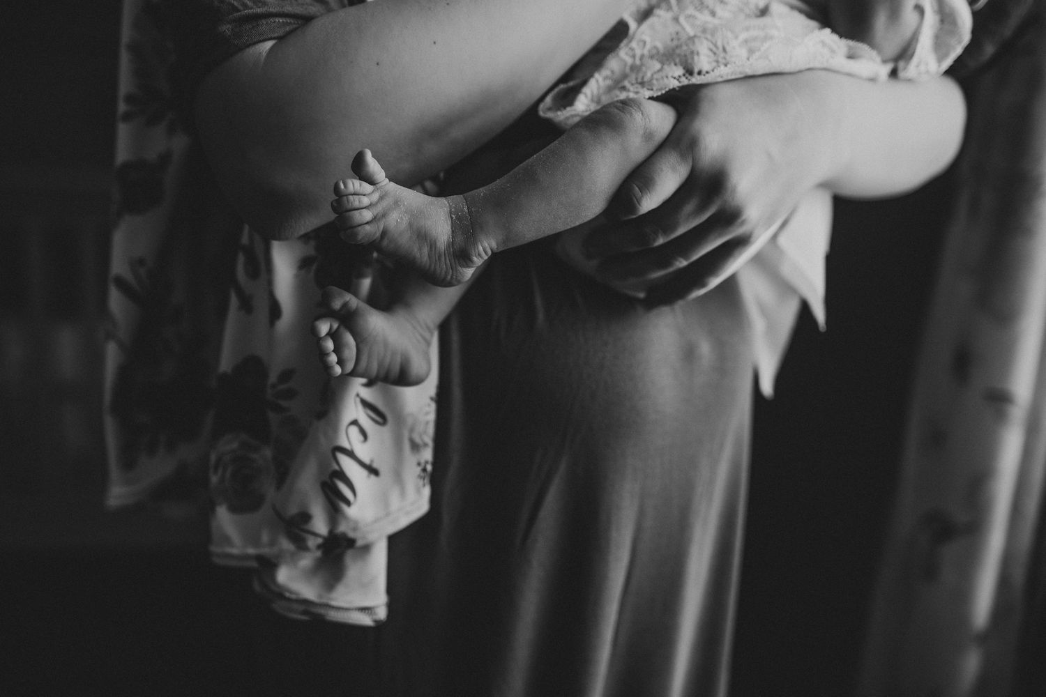 Black and white image of person holding infant in flowing dress.