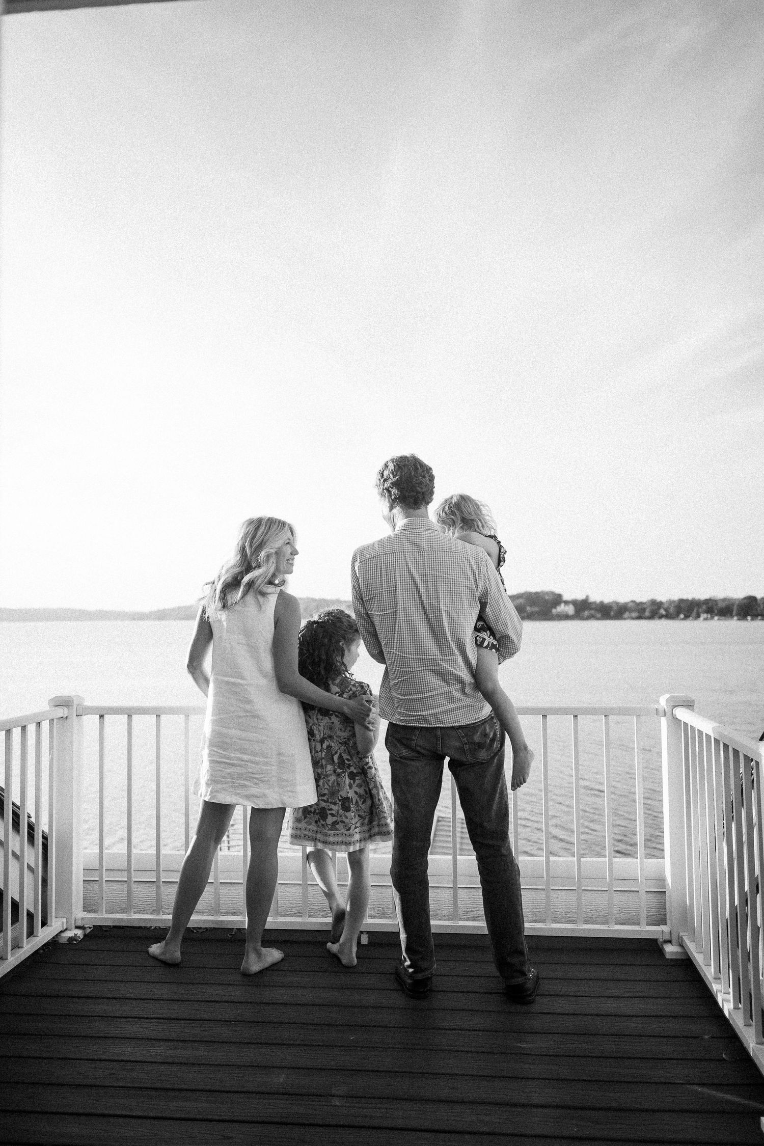 A family enjoys a peaceful moment together on a waterfront deck overlooking a serene lake view.