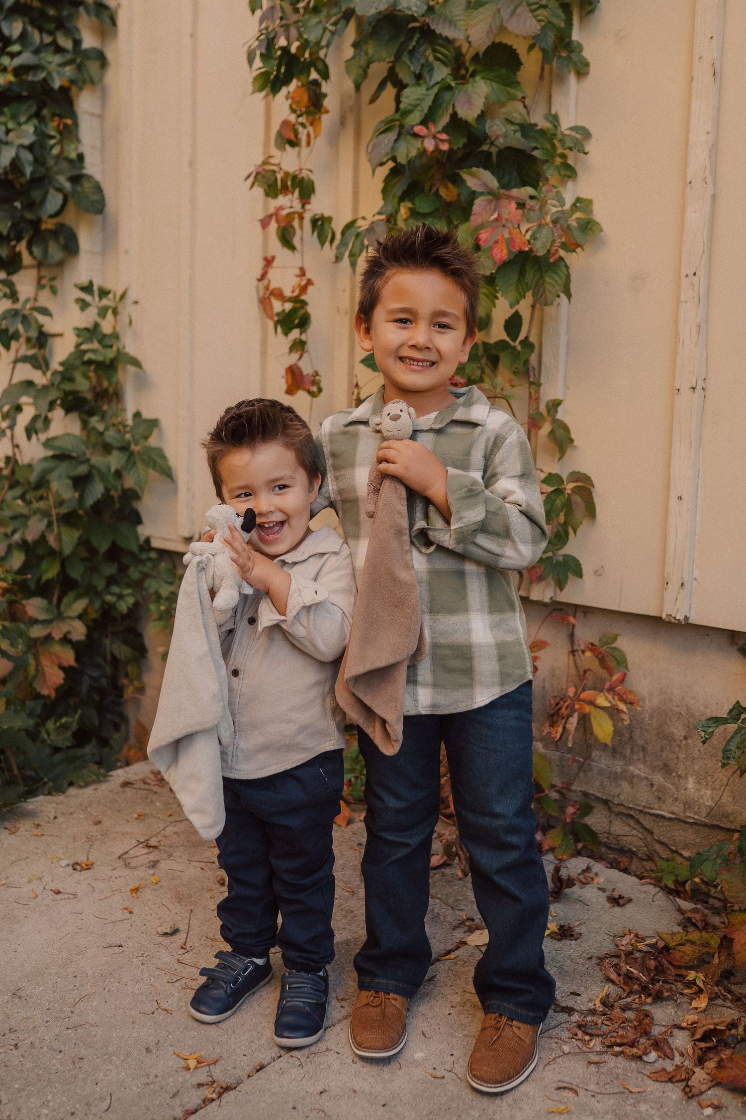 Two people sharing playful moments against a beige wall with climbing vines.