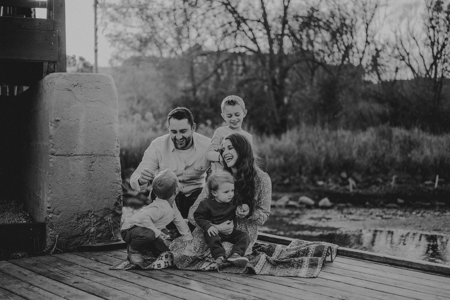 Black and white candid family photo on wooden deck at dusk.